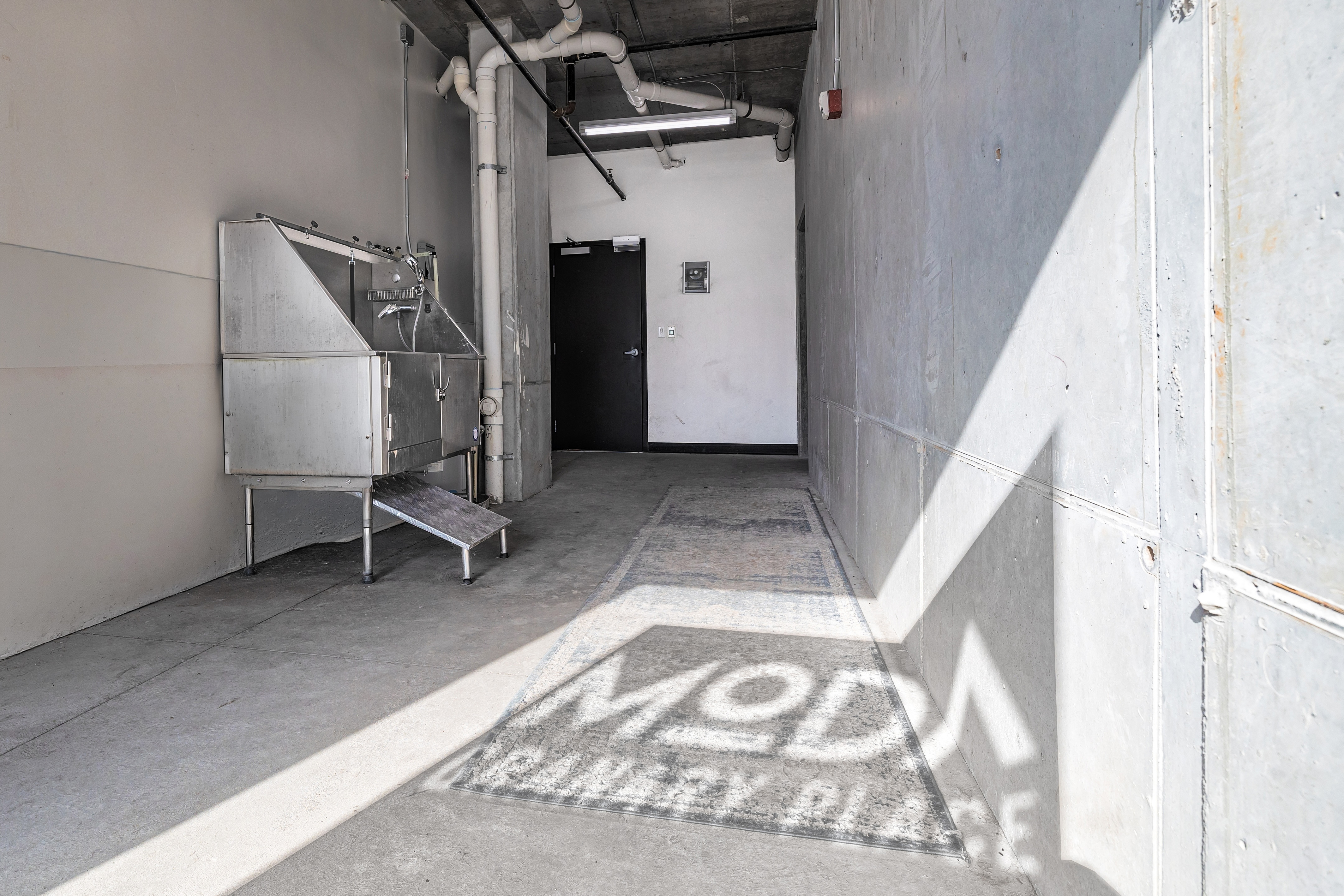 Contemporary industrial-style utility area with sleek metal wash station and geometric shadows.