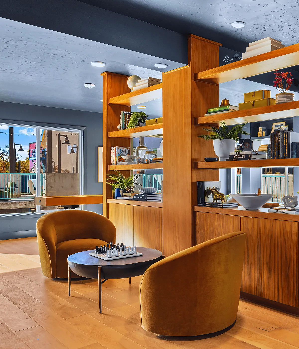 Contemporary lounge area with stylish seating and wooden shelving, featuring a cozy setting for relaxation.