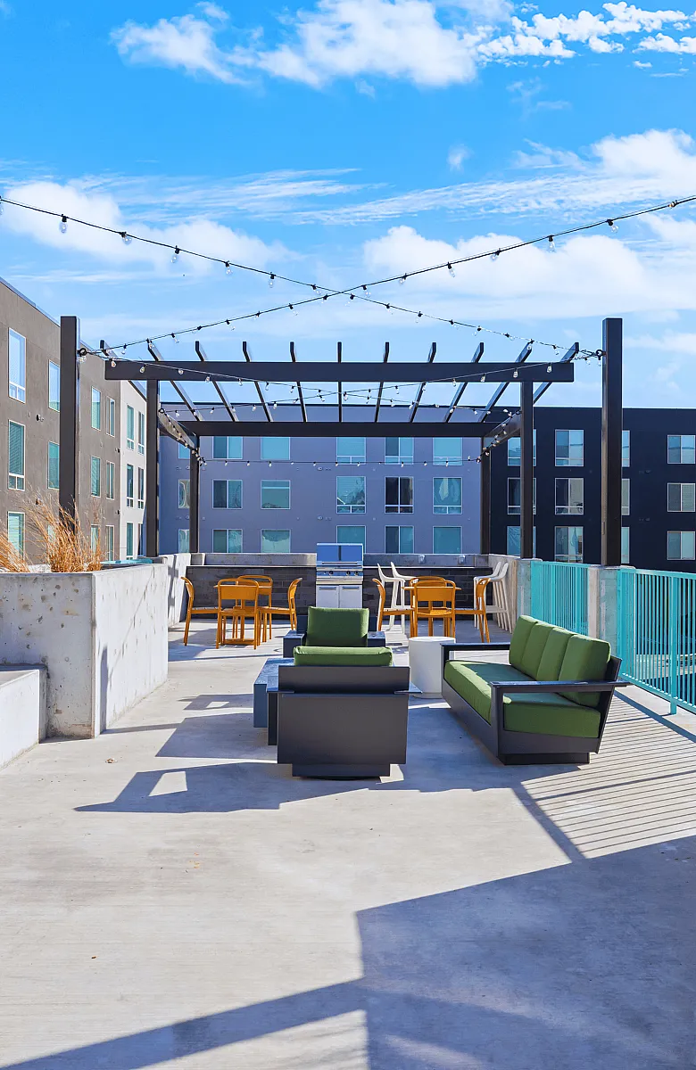 Modern outdoor patio with stylish seating and vibrant decor under string lights.