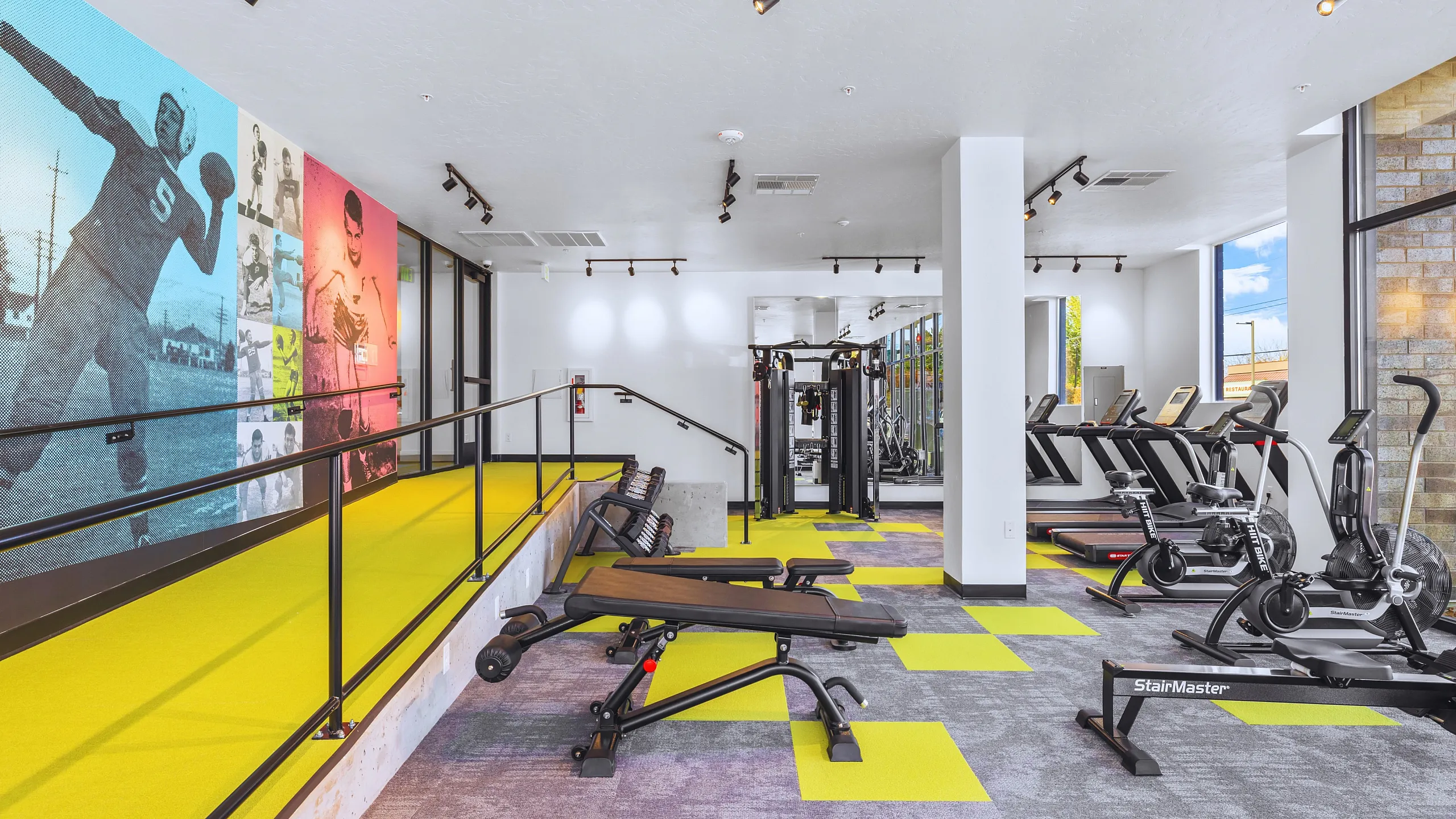 Modern gym with colorful sports mural, exercise equipment, and bright flooring