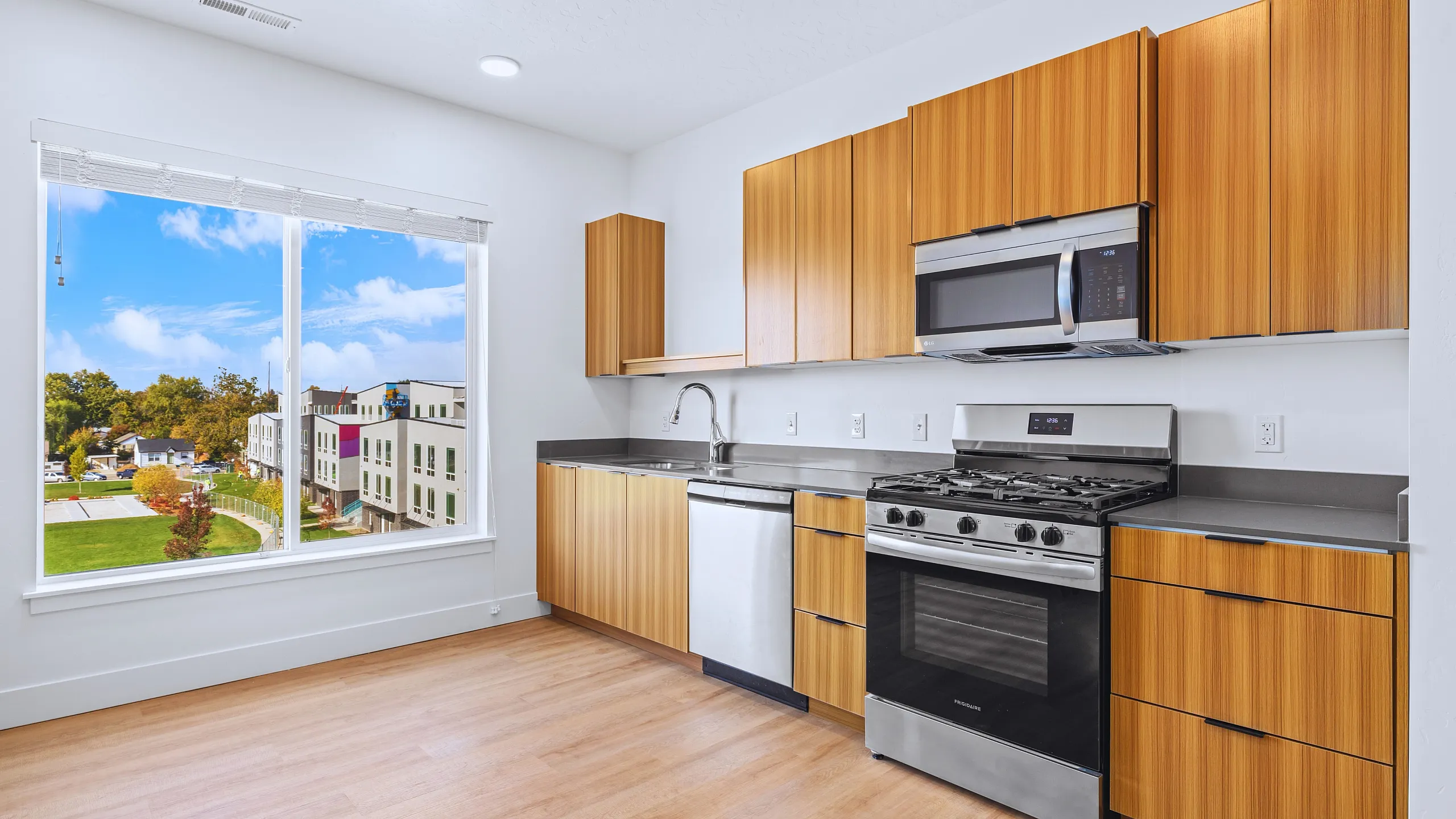 Bright kitchen with wooden cabinets, stainless steel appliances, and large window view.