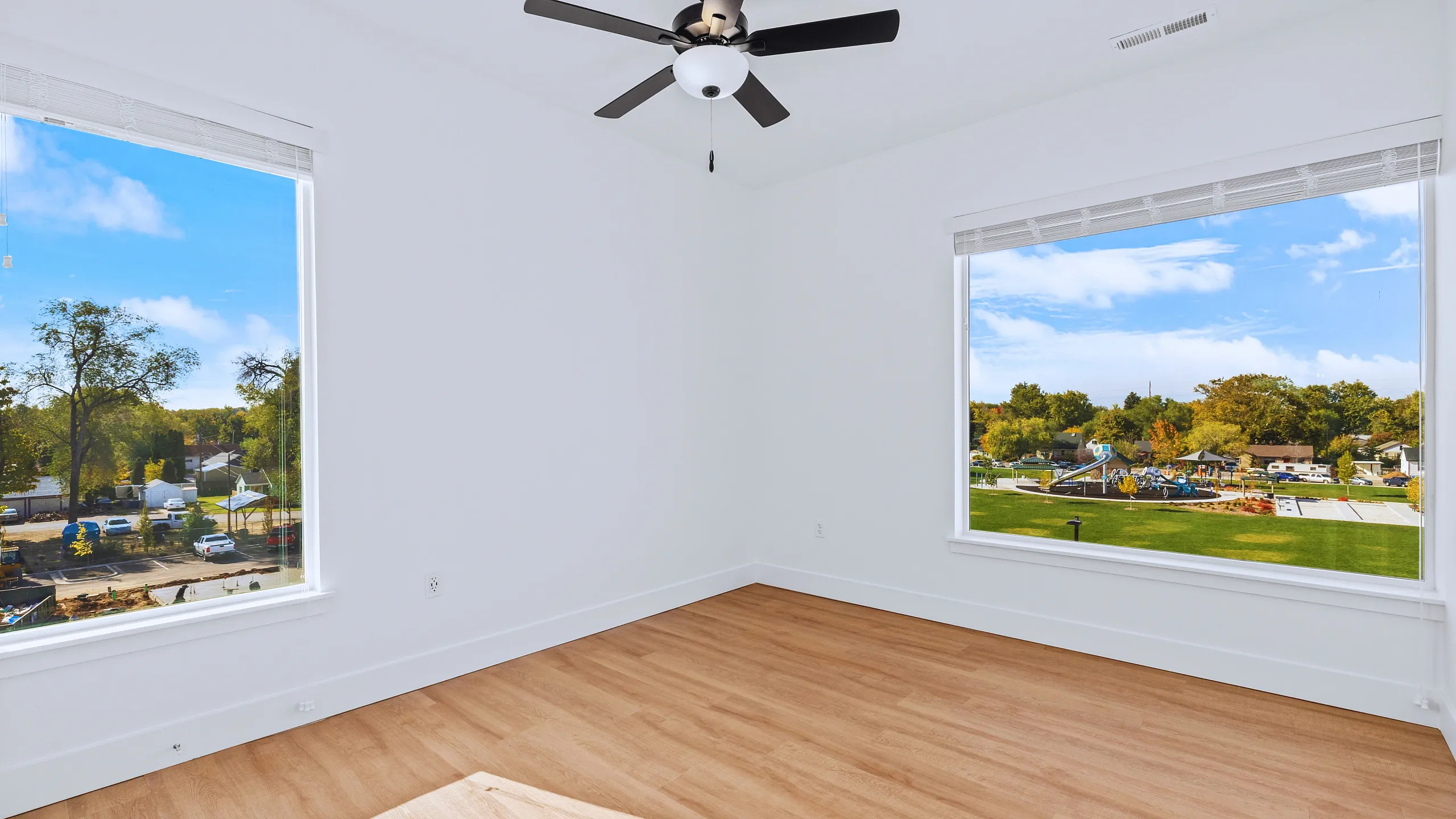 Spacious bright room with large windows showcasing scenic park views and hardwood flooring.