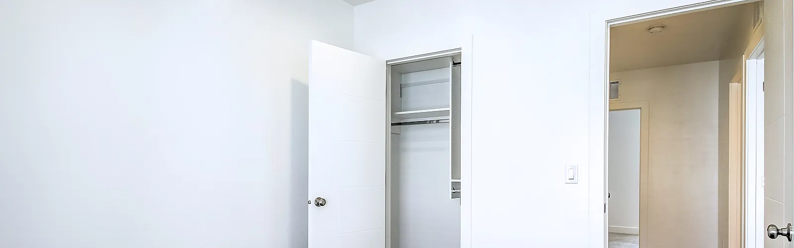 Bright and airy bedroom with open closet and soft carpet flooring.