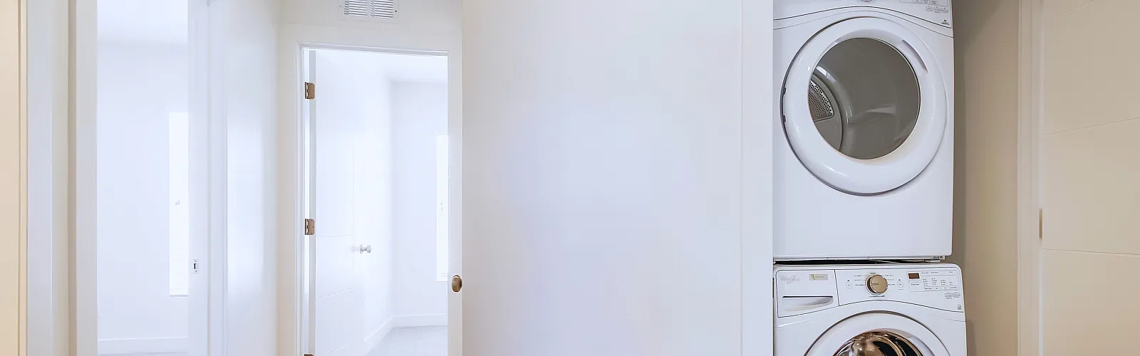 Bright hallway with stackable washer and dryer neatly tucked in a modern apartment unit.