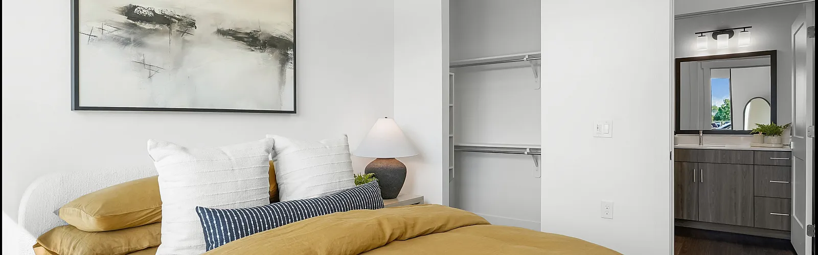 Bright, modern bedroom showcasing elegant decor with stylish artwork and an en-suite bathroom for luxurious living.