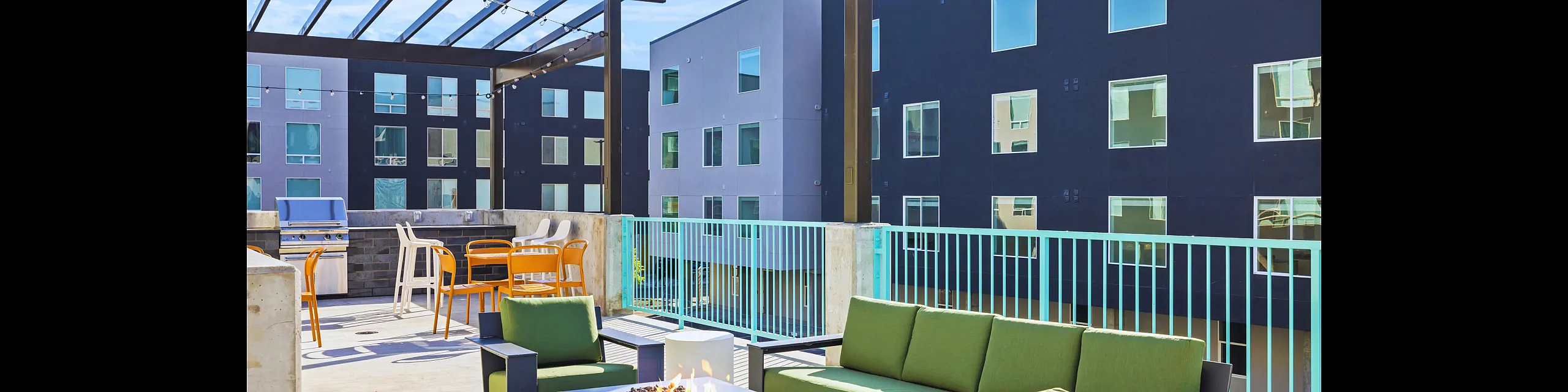 Chic rooftop patio with vibrant green seating, modern fire pit, and elegant pergola under a clear blue sky.