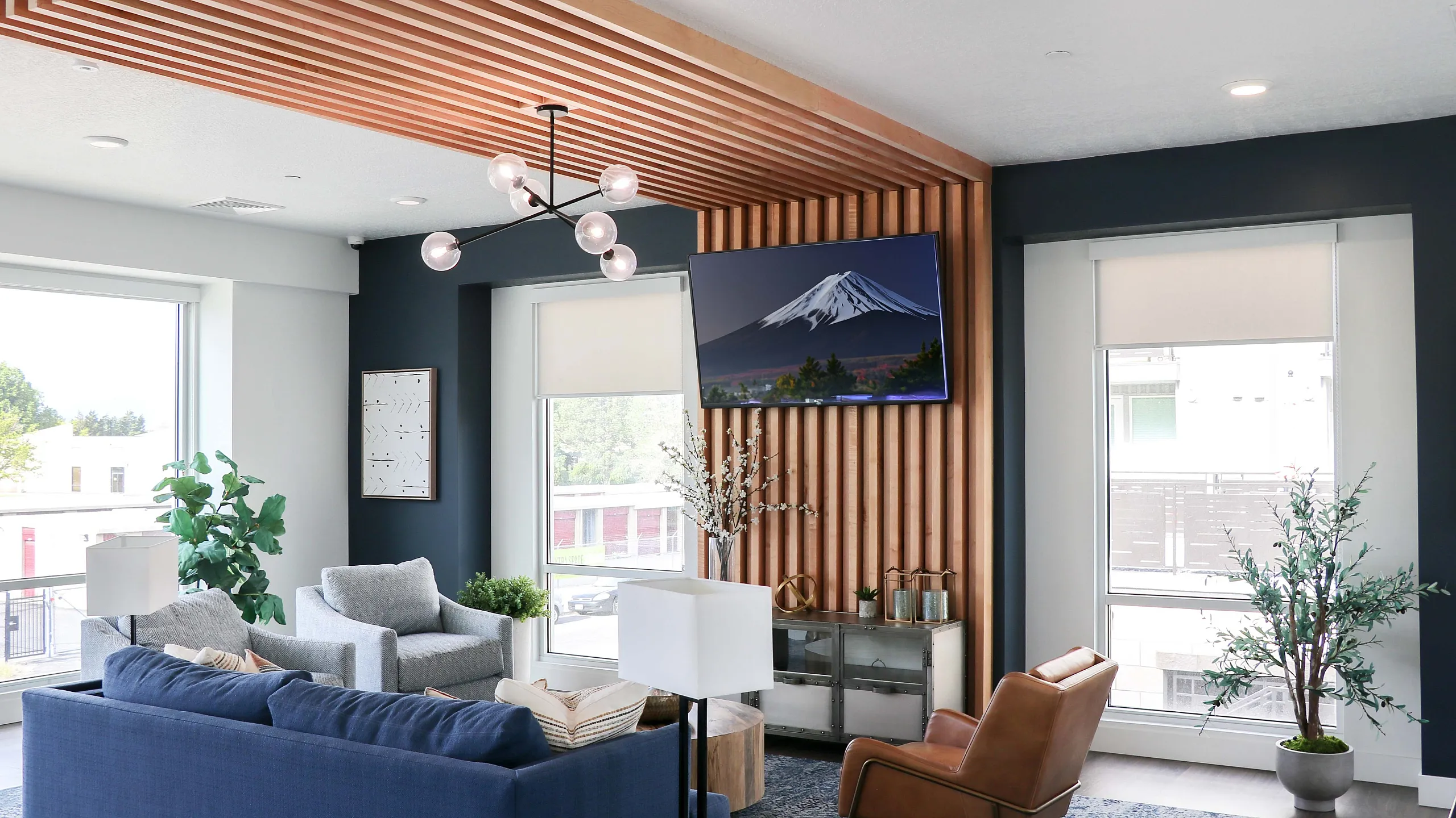 Chic modern living room with stylish wooden ceiling accents, large windows, and elegant decor including a mounted TV and contemporary furniture.