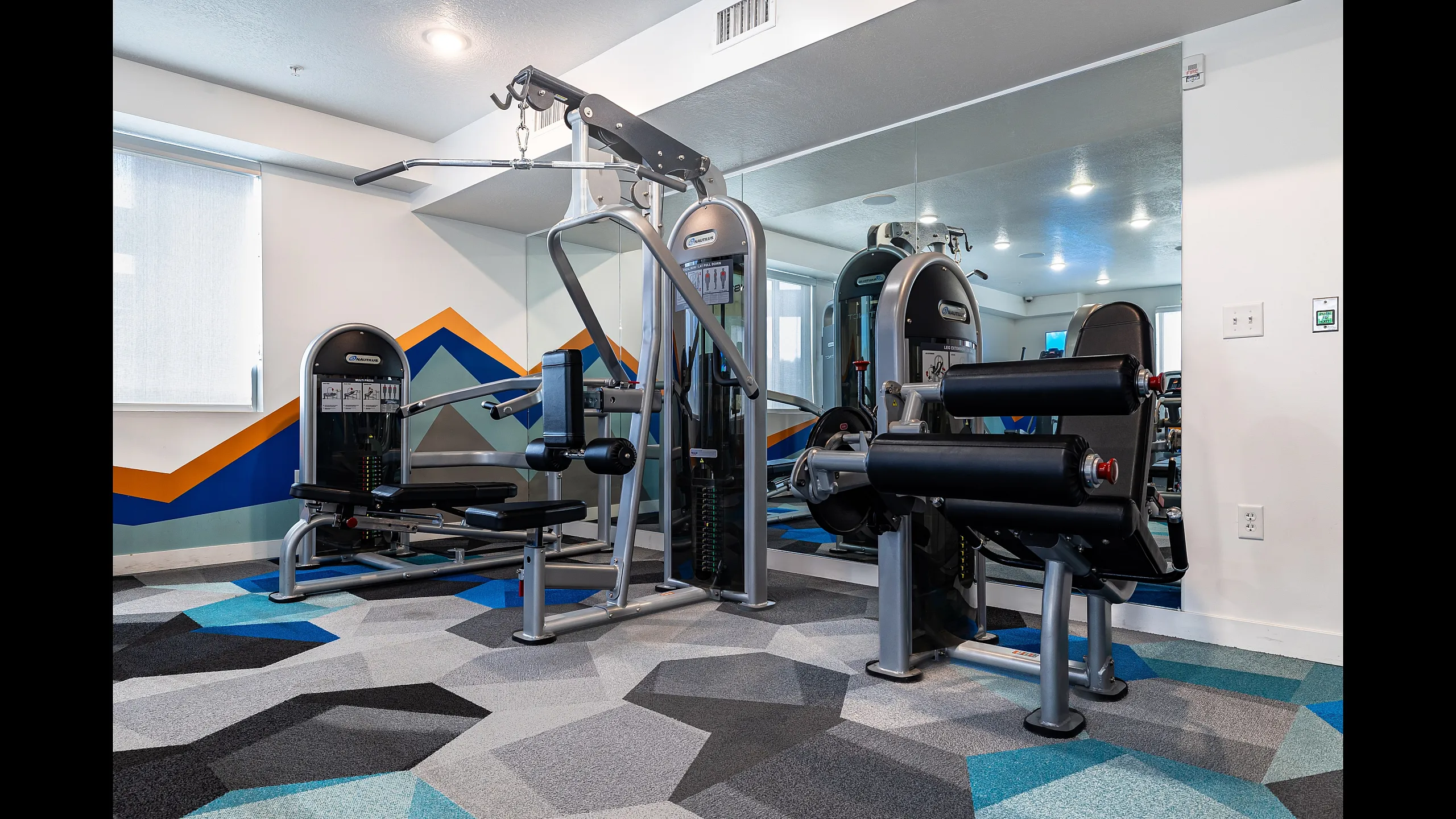 State-of-the-art fitness room featuring modern gym equipment and vibrant geometric design flooring.