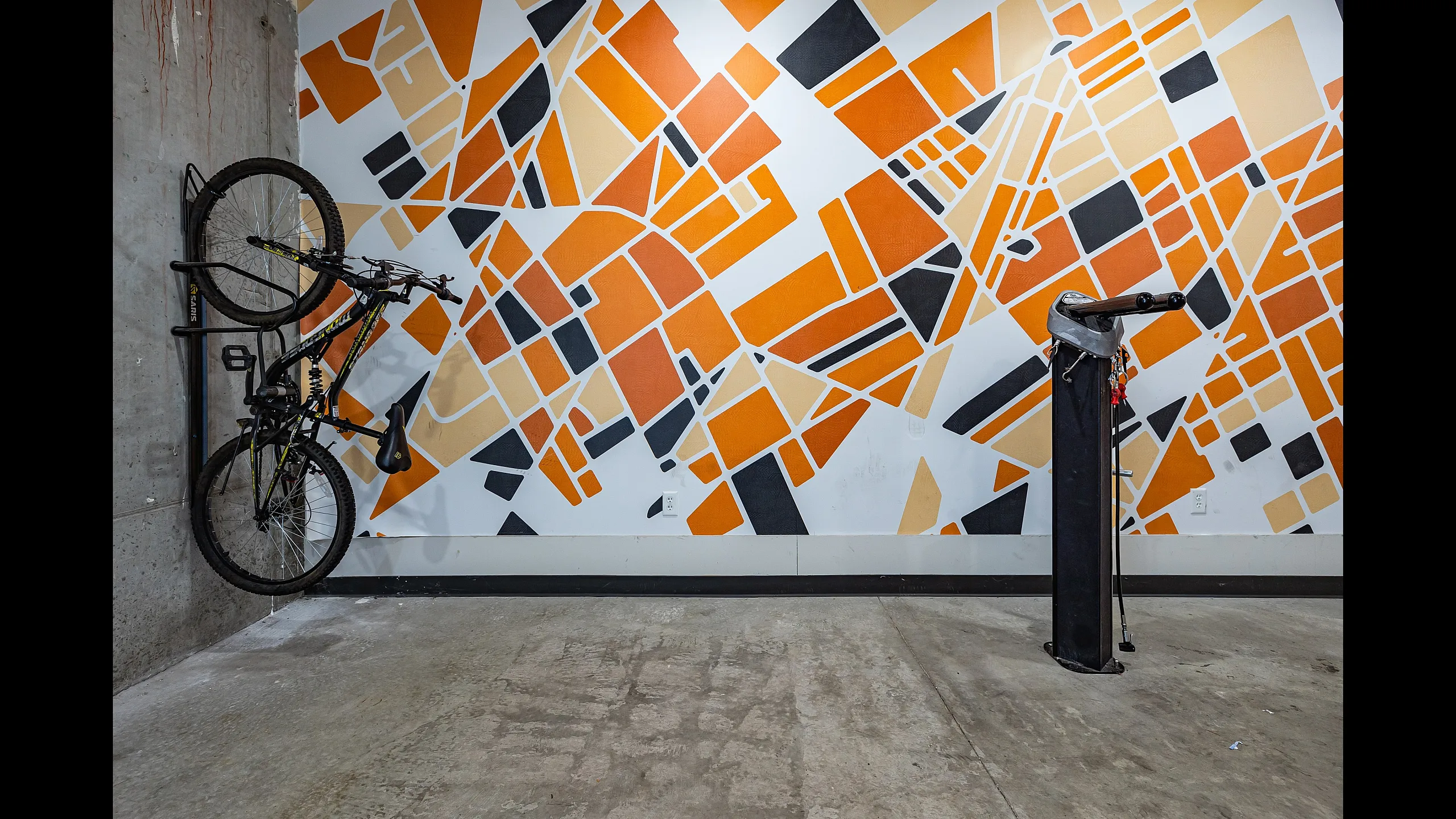 Modern bike storage area with a vibrant geometric mural in orange, black, and beige, creating a stylish urban ambiance.