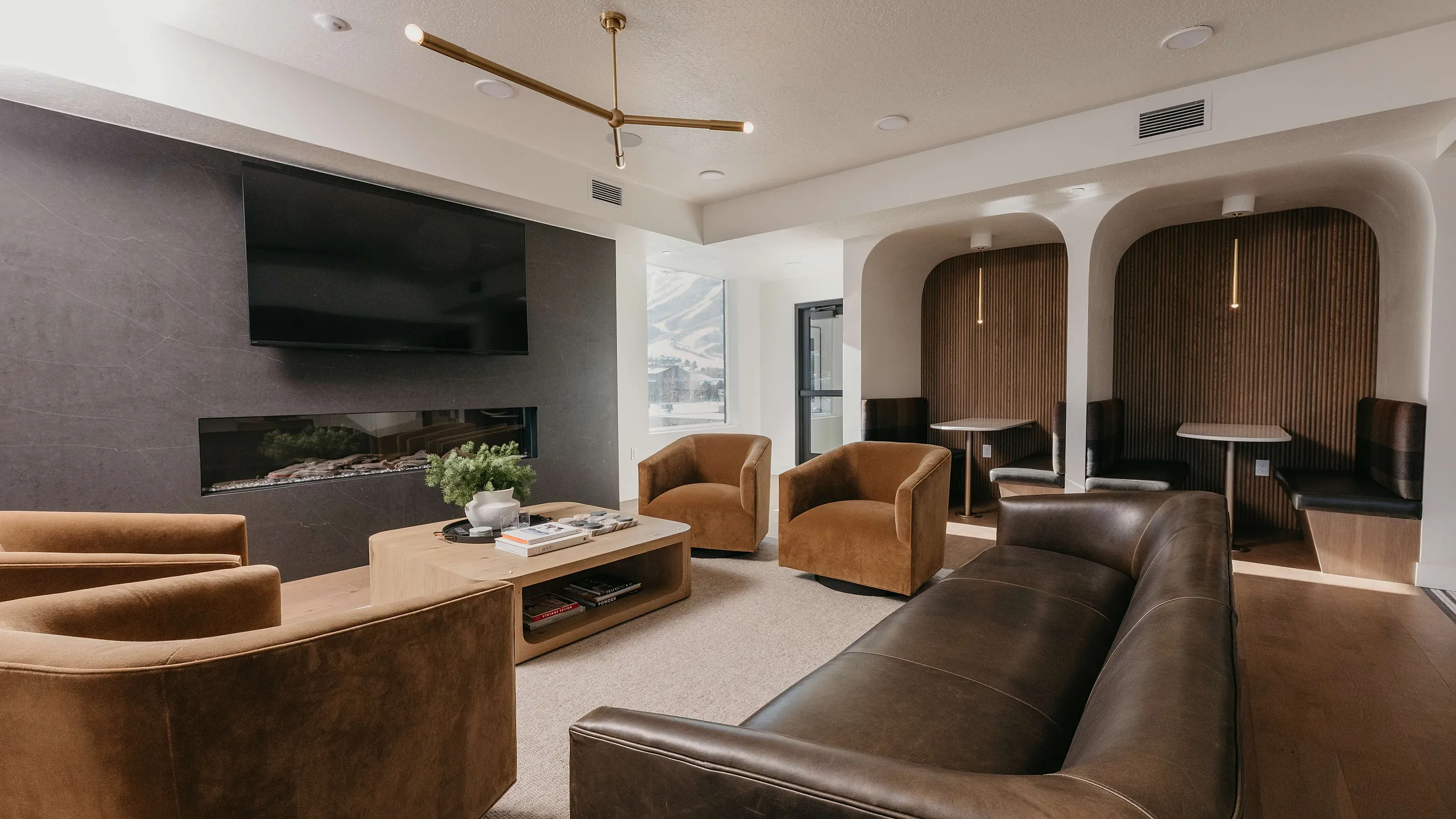 Contemporary living room featuring a sleek fireplace, plush velvet chairs, a stylish leather sofa, and cozy built-in seating nooks.