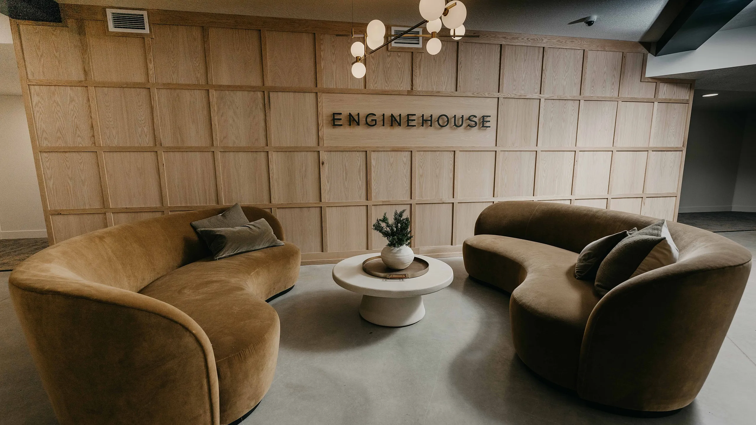 Modern and inviting lobby space featuring plush curved sofas, a central coffee table, and stylish pendant lighting.