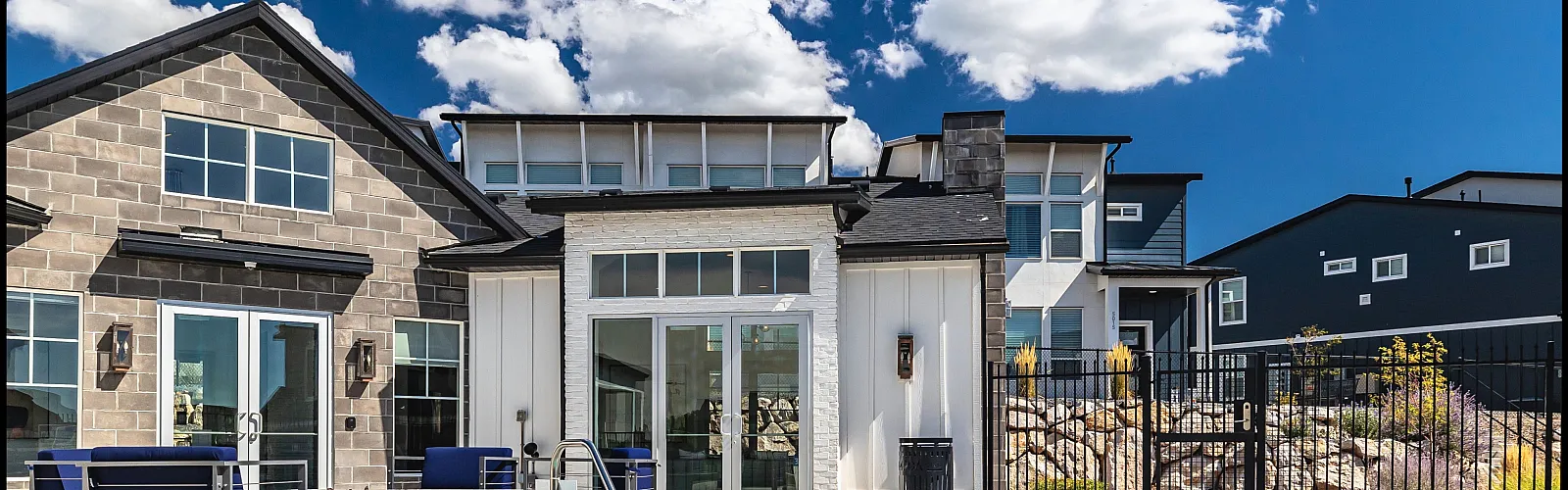 Charming apartment community featuring a modern clubhouse with a refreshing pool, vibrant seating, and stunning architectural design under a bright blue sky.