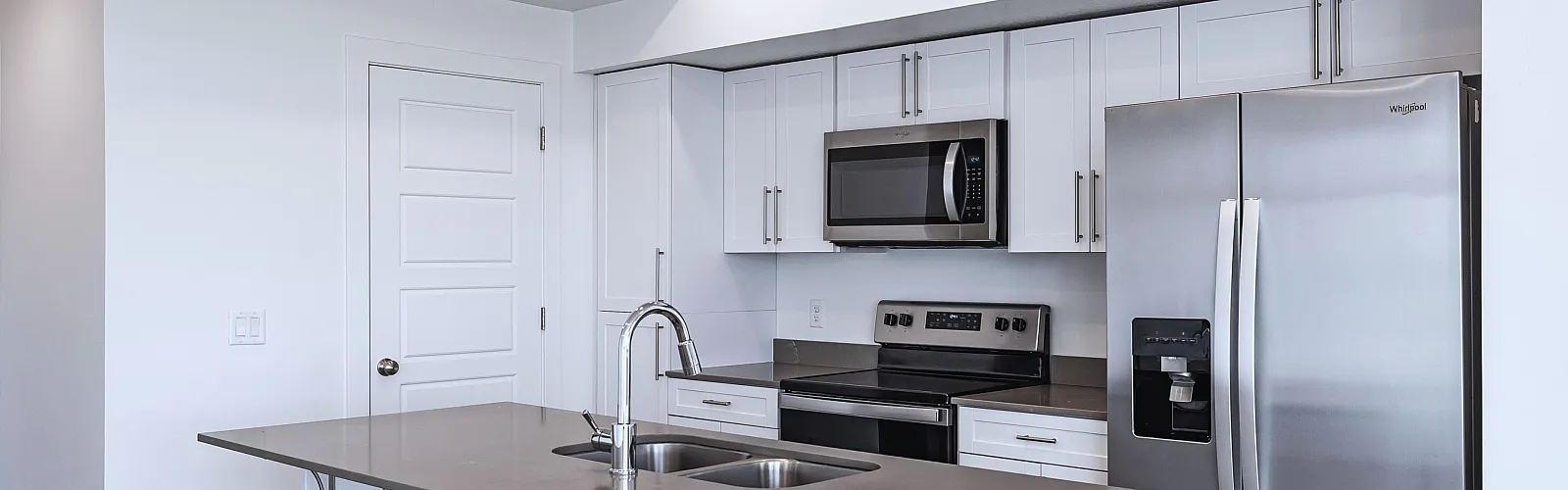 Modern kitchen with sleek white cabinetry, stainless steel appliances, and stylish wood flooring.