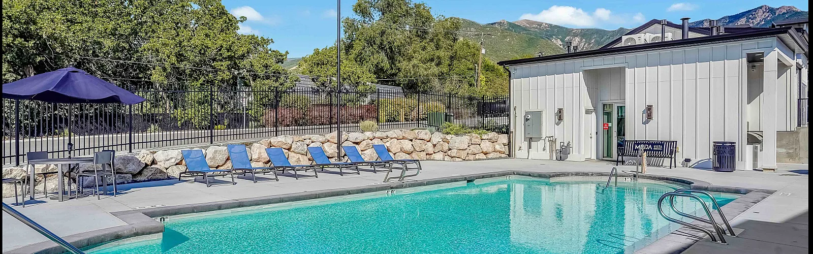 Inviting outdoor pool area with crystal-clear water, surrounded by lounge chairs and a scenic mountain backdrop, perfect for relaxation and leisure.
