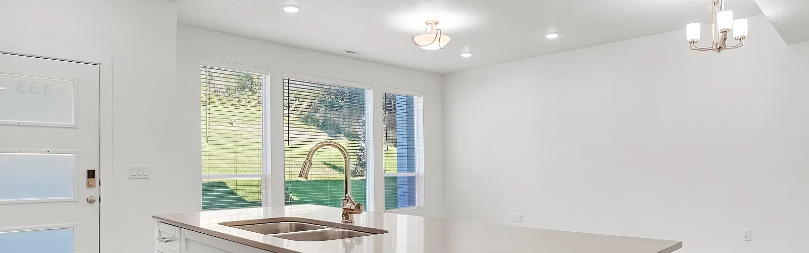 Modern open-concept kitchen with sleek white cabinetry, stainless steel appliances, and large windows offering scenic views.