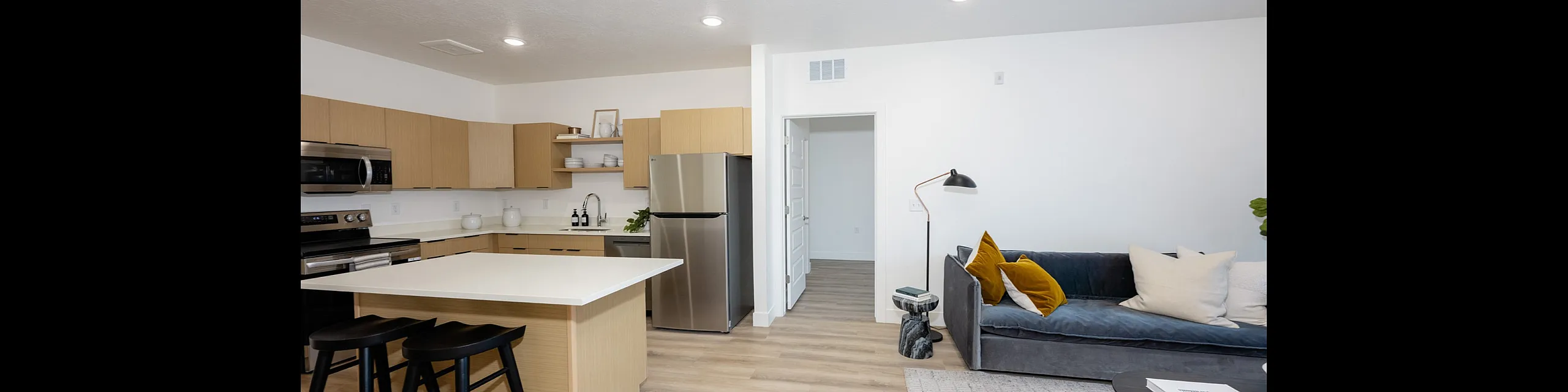 Modern open-plan living area with sleek kitchen, island seating, and cozy lounge space featuring stylish decor.