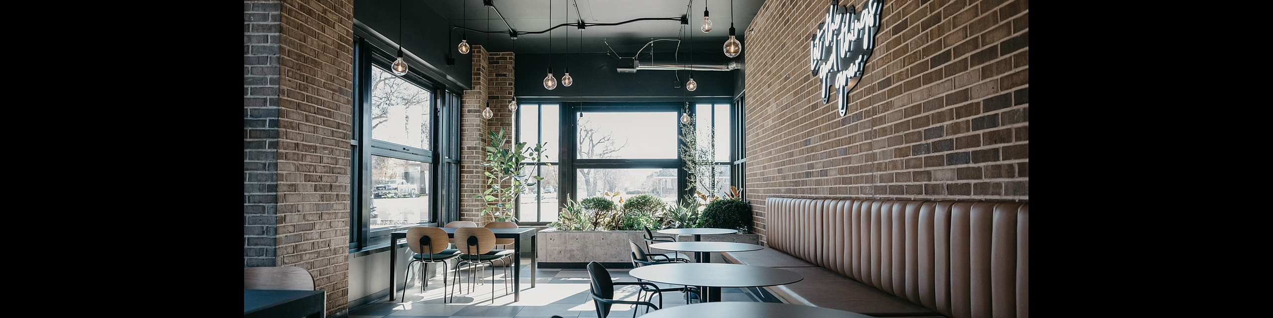 Chic and modern cafe interior with stylish brick walls, cozy seating, and ample natural light from large windows.