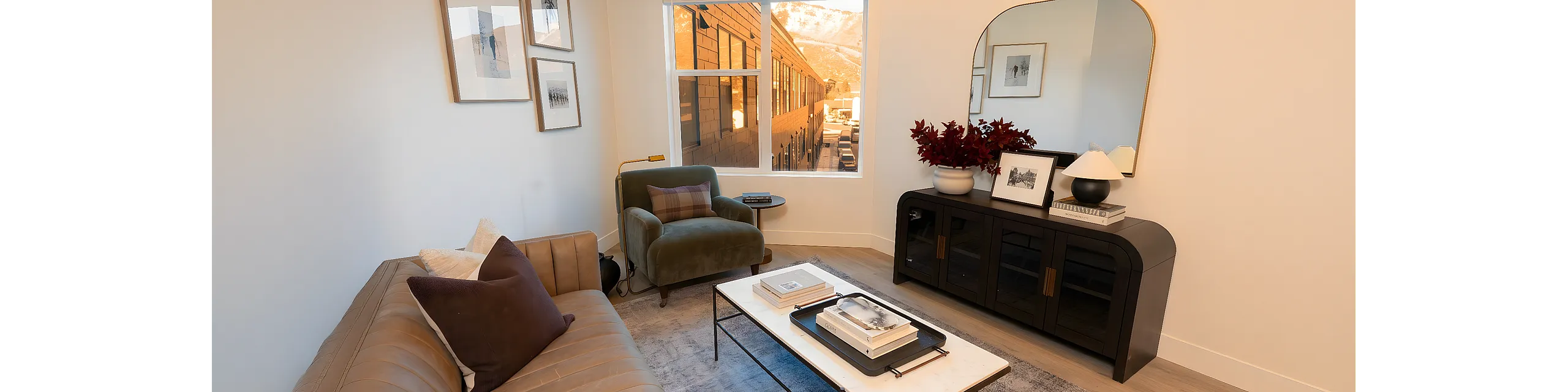 Inviting living room with modern decor, plush seating, and elegant artwork, bathed in natural light with a picturesque exterior view.