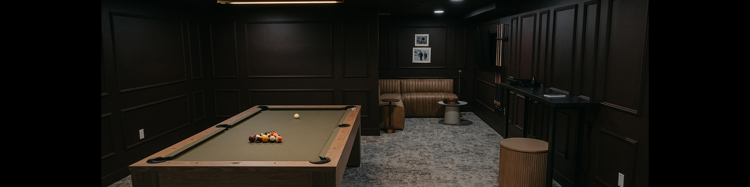 Elegant billiards room with a modern pool table, cozy seating nook, and ambient lighting, perfect for relaxation and entertainment.
