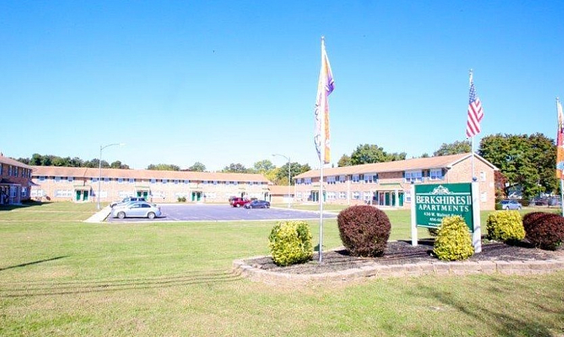 Charming Berkshires II Apartments with lush landscaping, ample parking, and inviting community flag display.