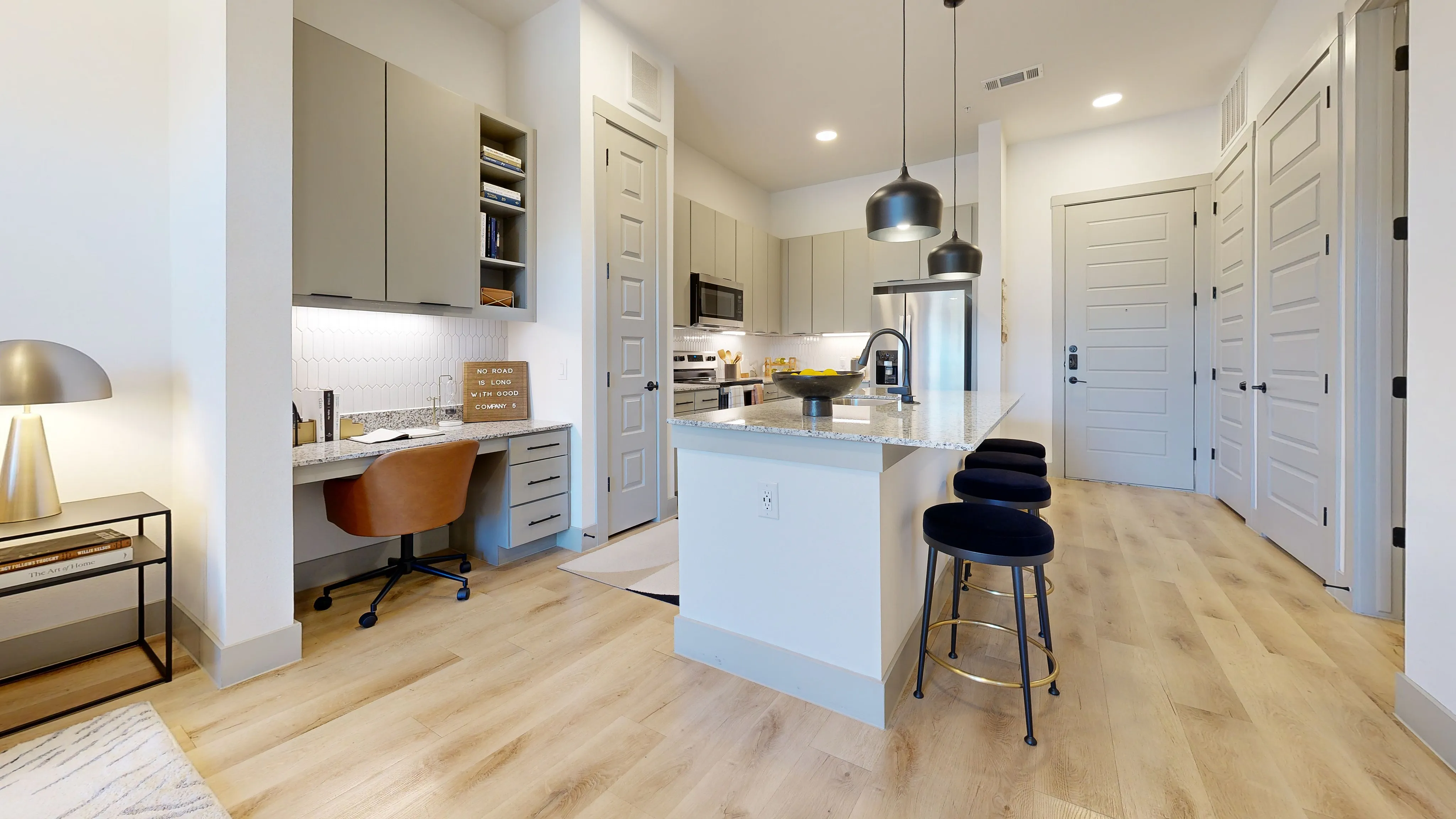 Modern kitchen with sleek cabinetry, granite countertops, stylish pendant lighting, and a cozy workspace, at Paloma Village.