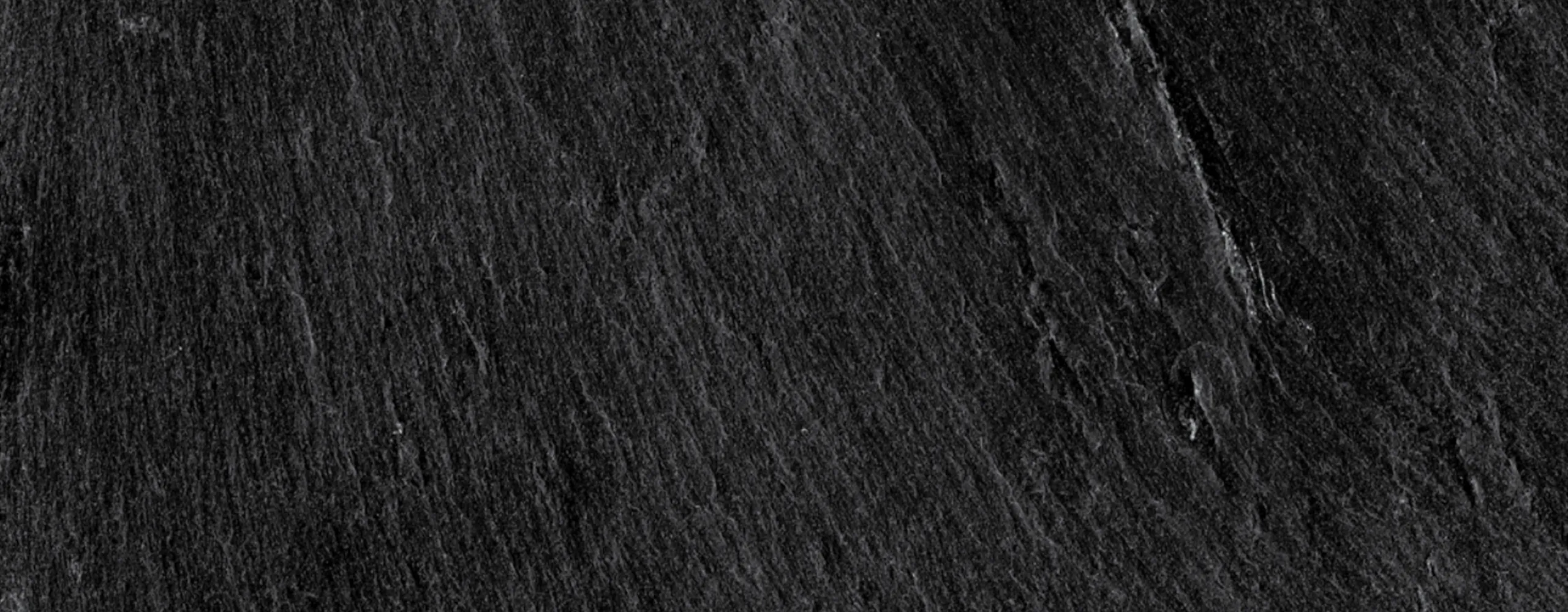 Close-up of a dark slate surface with natural texture and rich color.