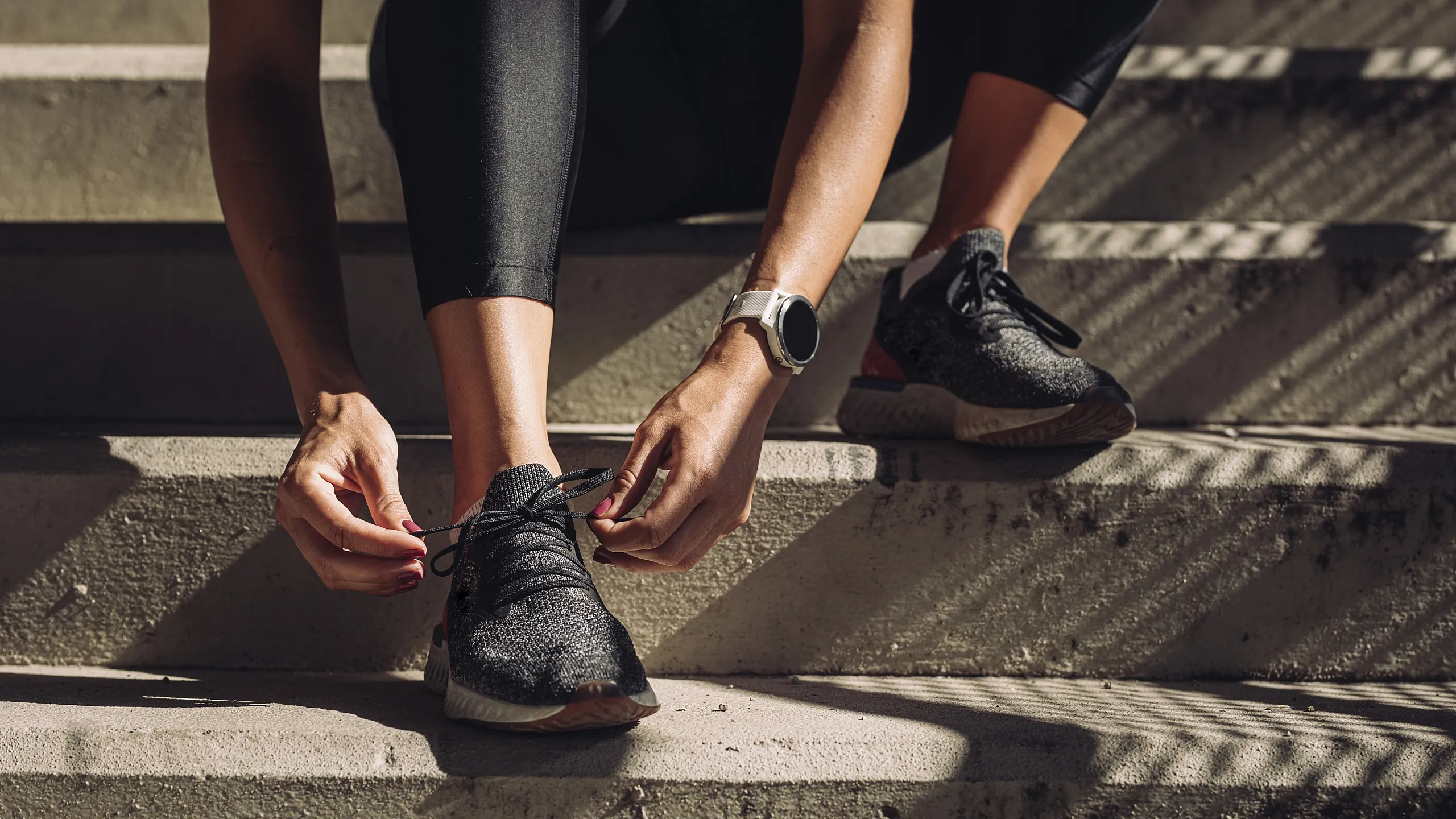 Dynamic close-up of a person tying shoelaces on athletic sneakers, embodying a readiness for fitness and outdoor adventure.