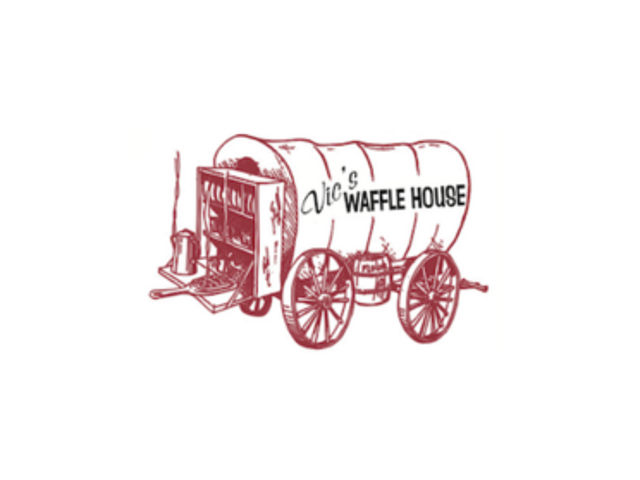 A red old fashioned covered wagon with the words Vic's Waffle House in it