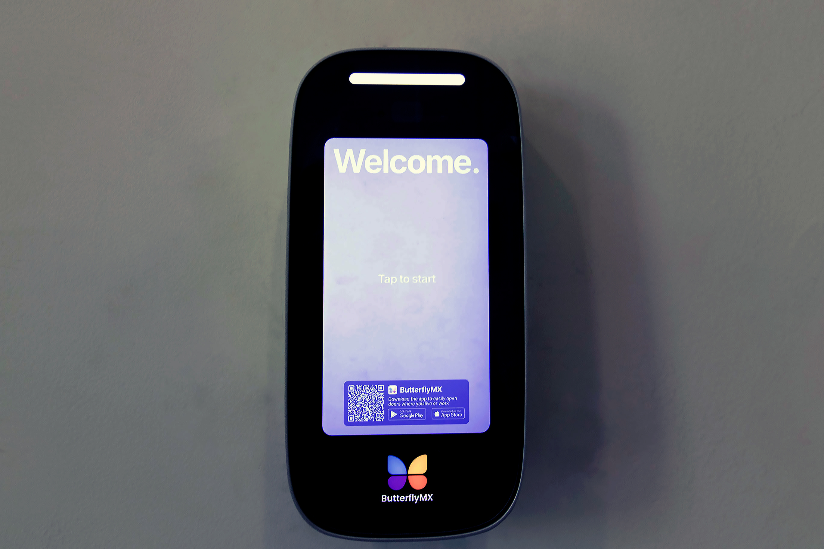 The James Apartments | Close-up of the ButterflyMX smart intercom system displaying a welcome screen with an option to tap and start | Luxury Apartments in Haverhill MA