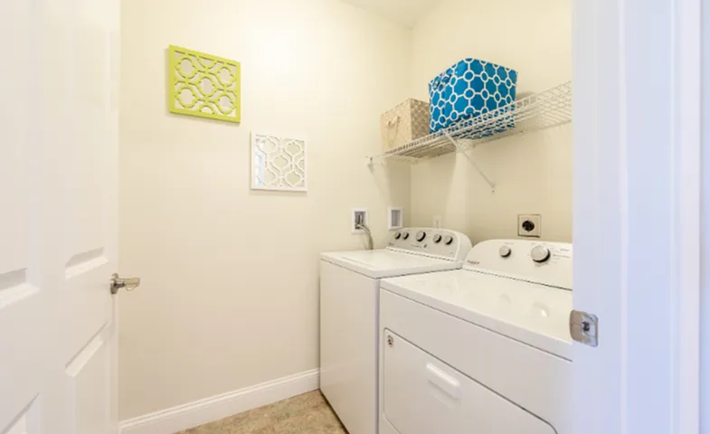 Chic laundry room with modern washer and dryer, enhanced by elegant decor and ample storage space.