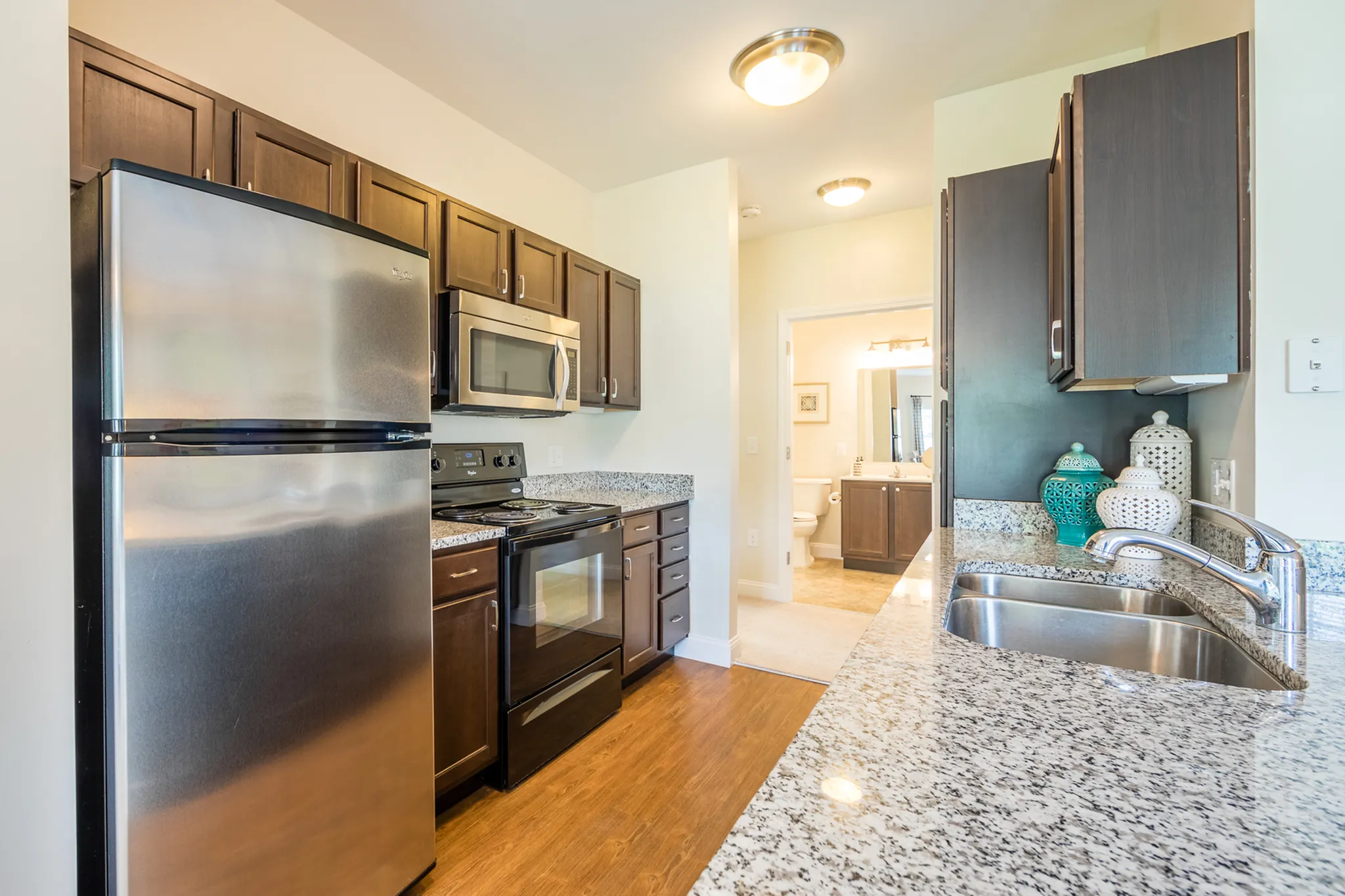 Modern kitchen with sleek stainless steel appliances, elegant granite countertops, and stylish dark wood cabinetry.