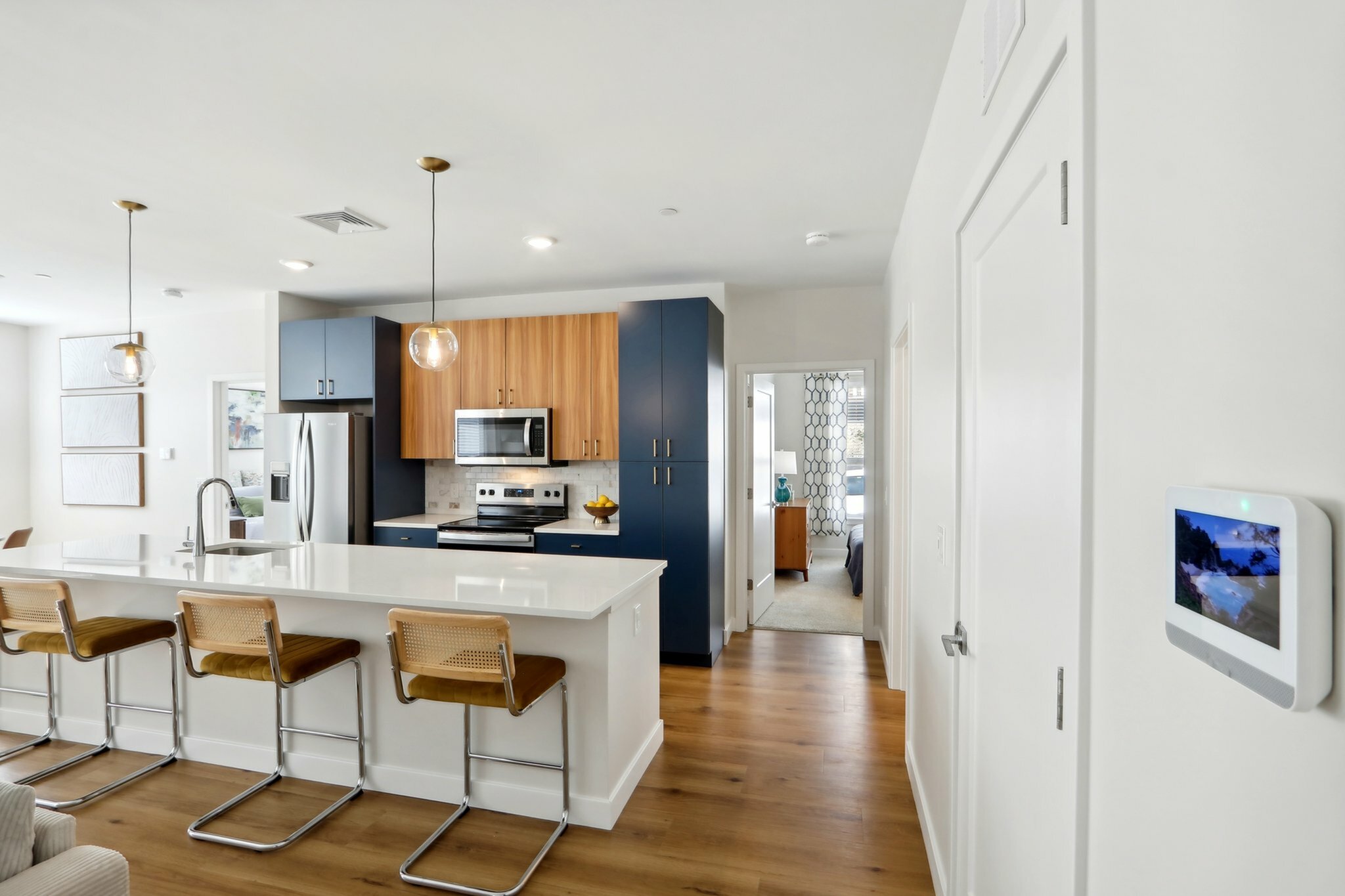Modern kitchen with sleek cabinetry, stainless steel appliances, and a spacious island with stylish barstools, leading to a cozy bedroom.