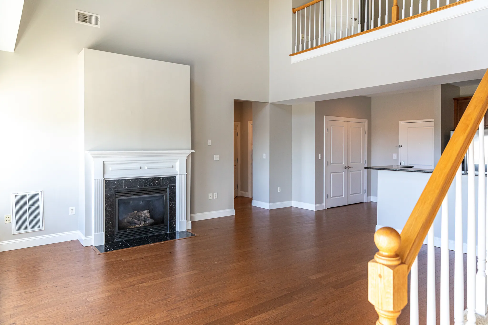 Bright and inviting living room showcasing elegant hardwood floors, a stylish fireplace, and a sleek modern railing leading to an upper level.