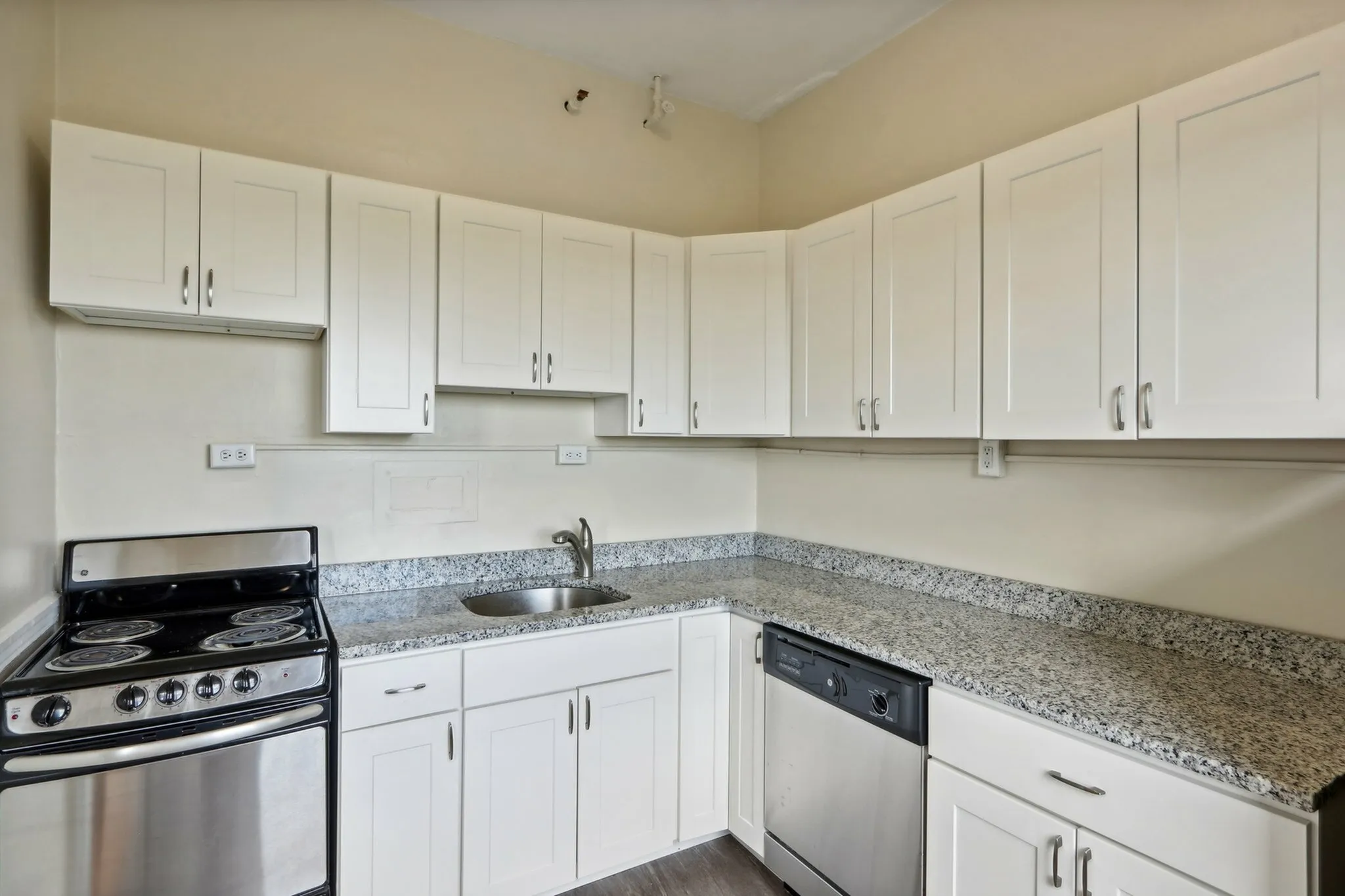 Modern kitchen with elegant granite countertops, sleek stainless appliances, and stylish white cabinetry.
