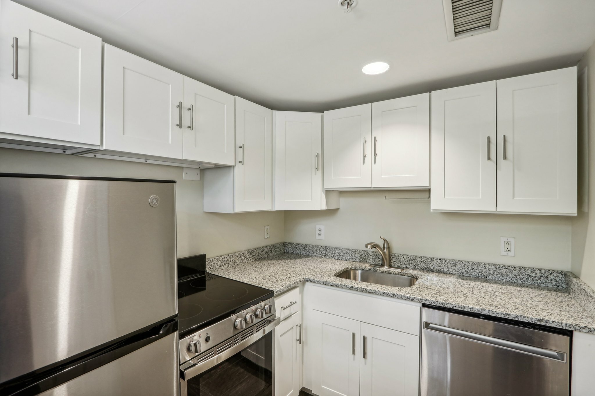 Modern kitchen with sleek stainless steel appliances, elegant white cabinetry, and stylish granite countertops.