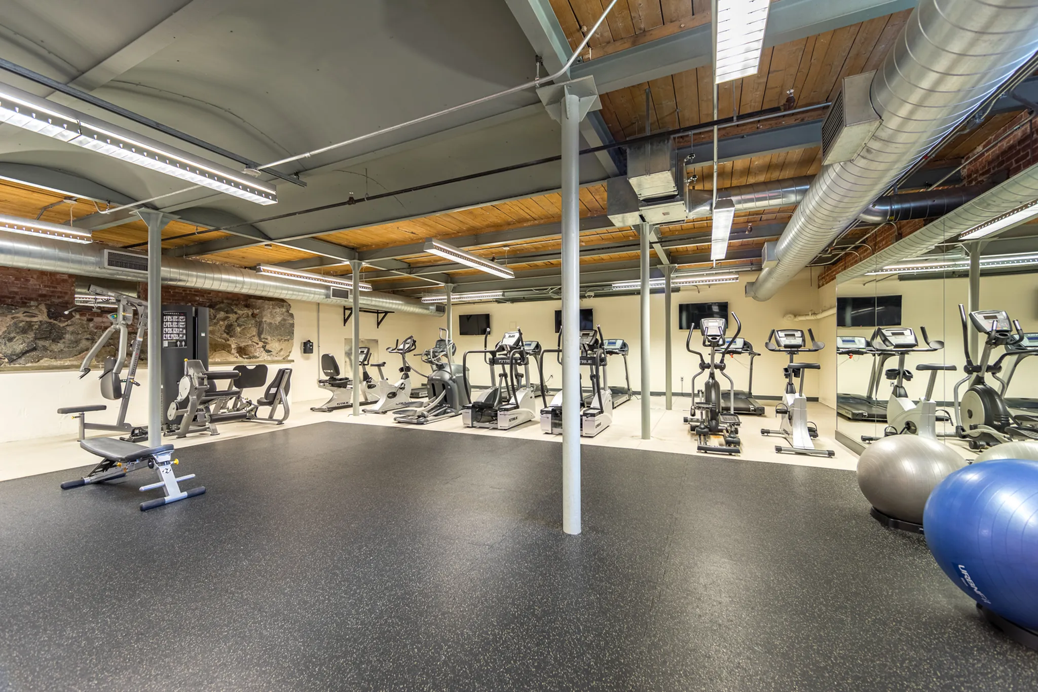 Spacious and well-equipped gym with modern exercise machines, polished floors, and industrial-chic design, perfect for a well-rounded workout experience.