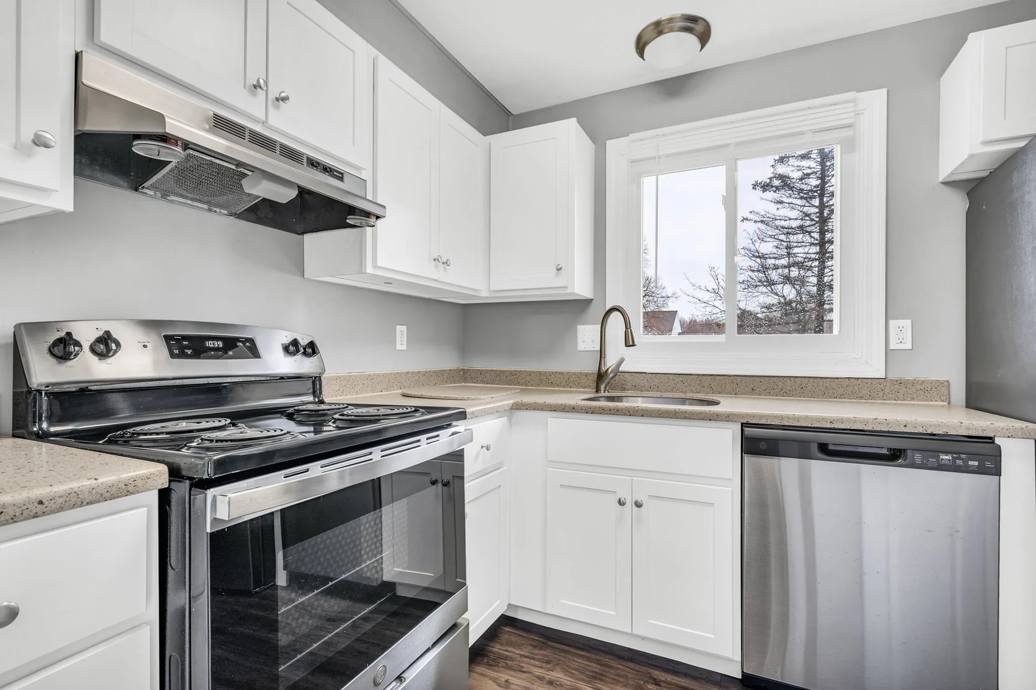 Bright modern kitchen with sleek stainless steel appliances, elegant white cabinetry, and large window for natural light.