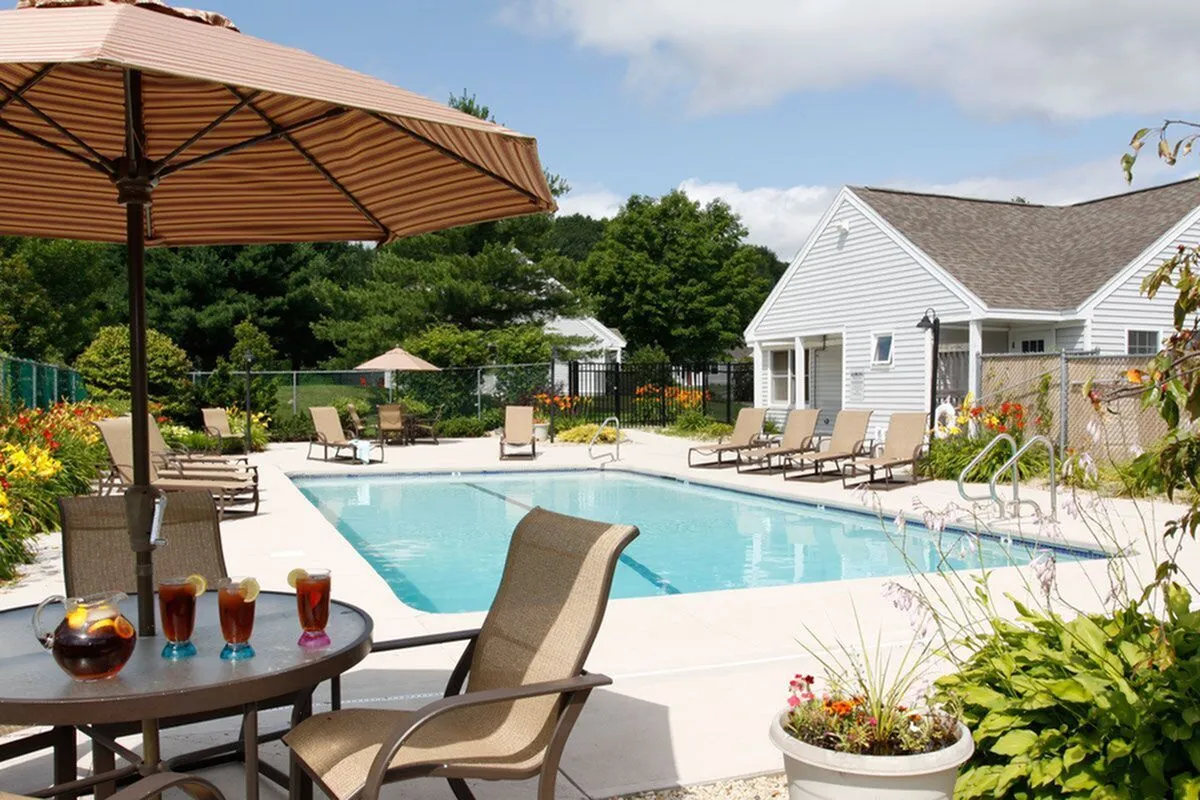 Inviting outdoor swimming pool surrounded by cozy sun loungers and vibrant gardens, perfect for relaxation and leisure.
