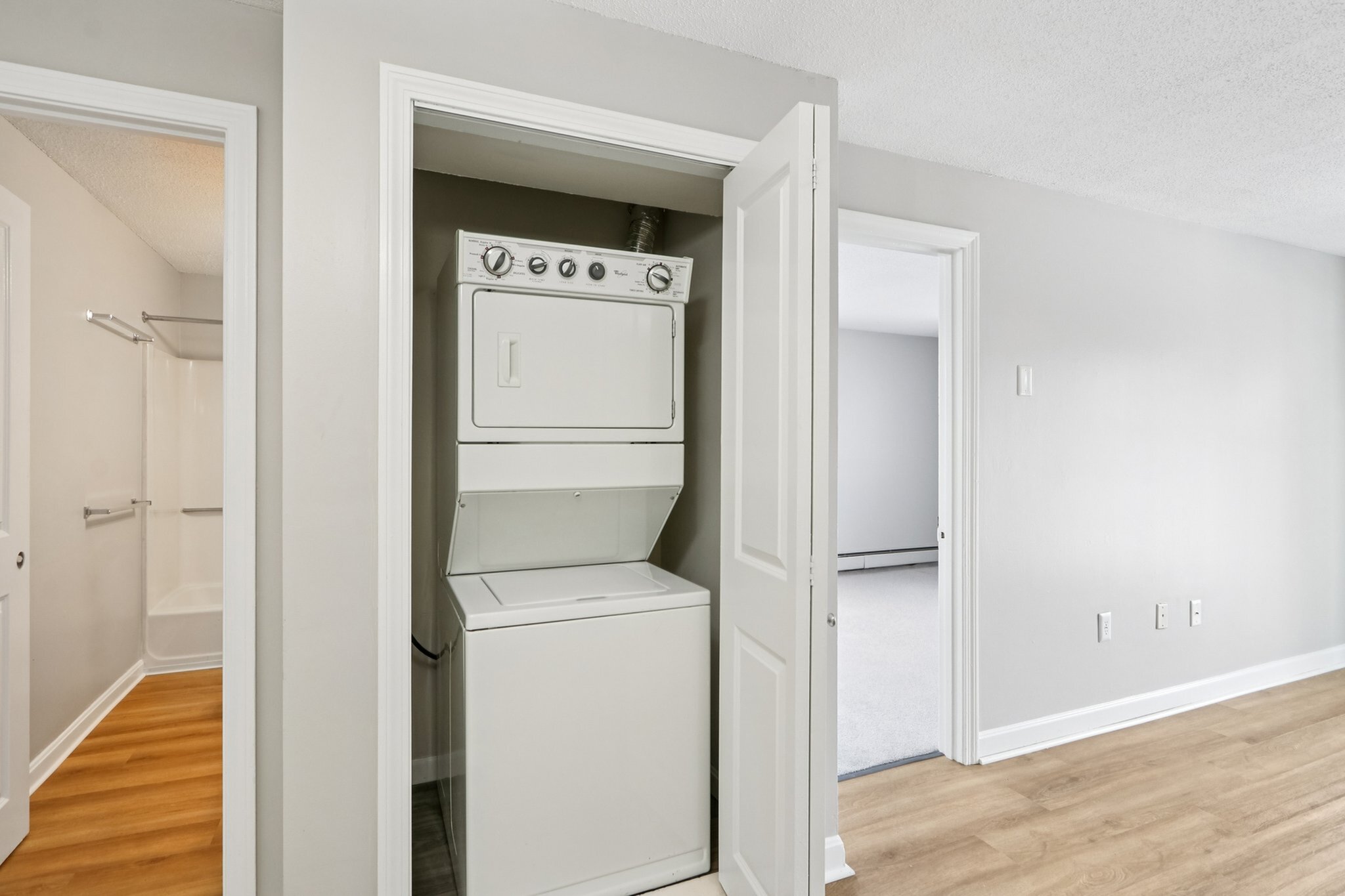 Modern apartment with in-unit stacked washer and dryer next to a sleek bathroom, offering convenience and style.