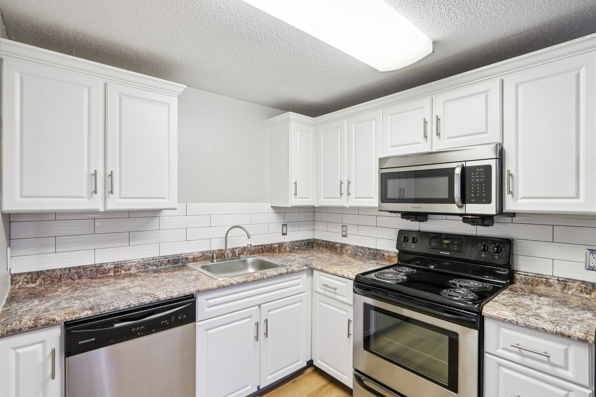 Bright, modern kitchen with sleek stainless steel appliances, elegant white cabinetry, and polished granite countertops.