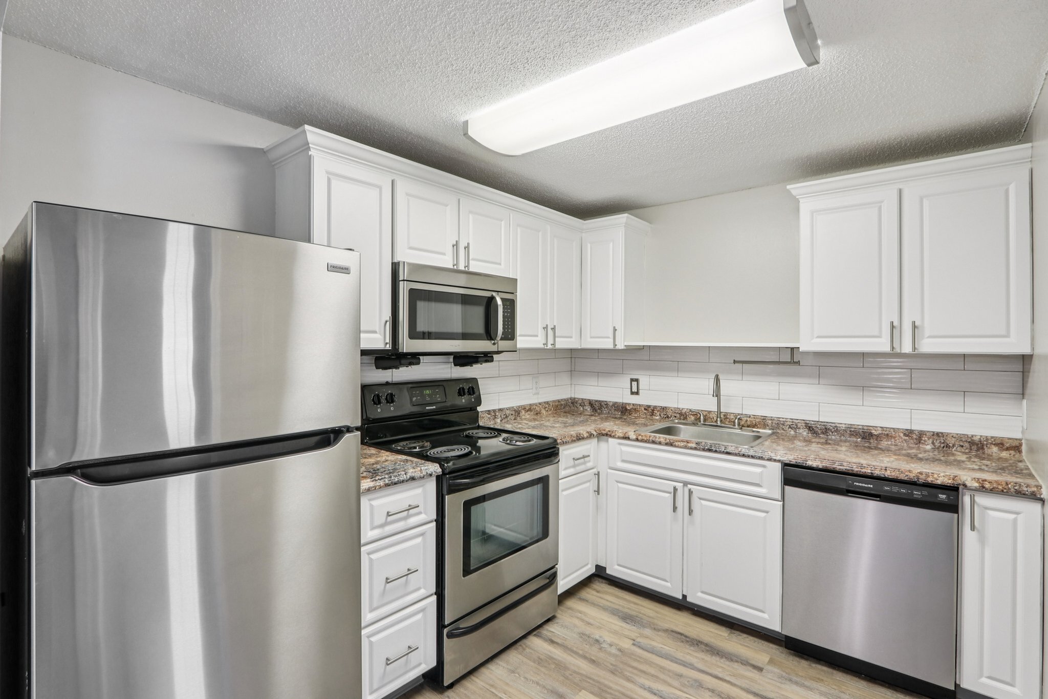Modern kitchen featuring sleek stainless steel appliances, pristine white cabinetry, and elegant marble countertops for a sophisticated touch.