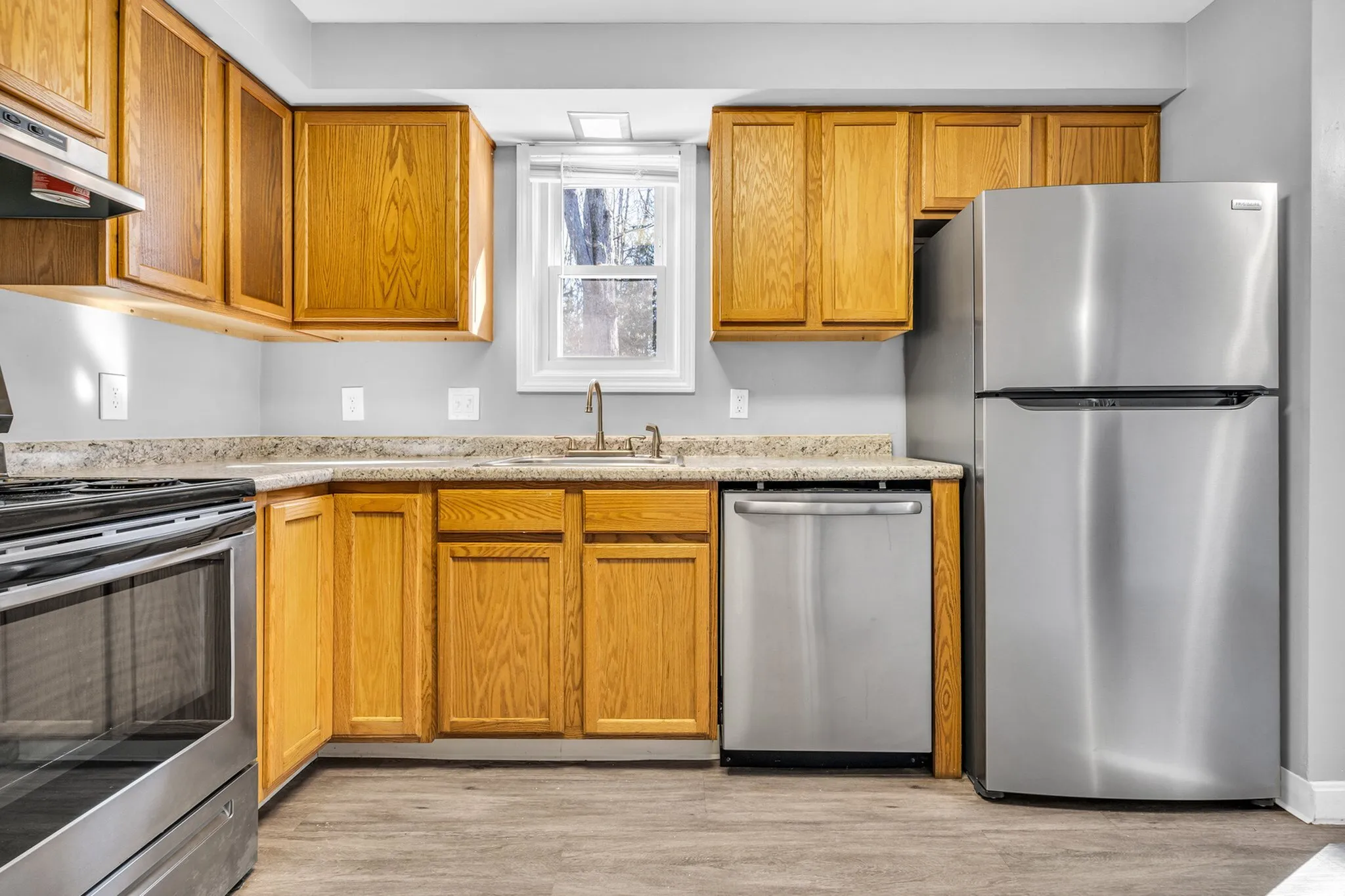 Modern kitchen with sleek stainless steel appliances, warm wooden cabinets, and a bright window view offering natural light.
