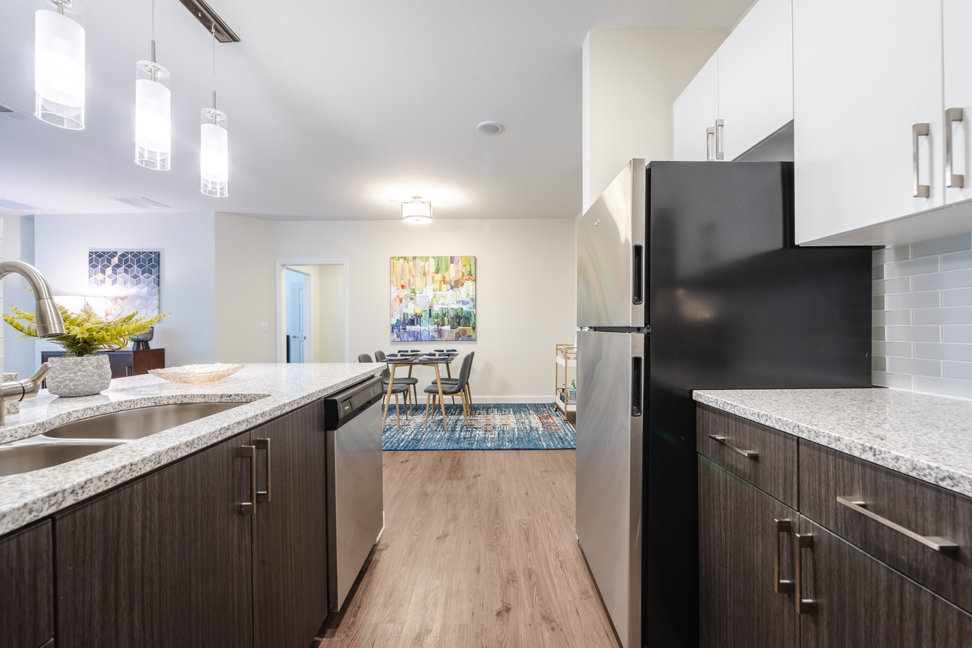 Modern kitchen with sleek countertops, stainless steel appliances, and stylish pendant lighting, seamlessly connected to a cozy dining area with contemporary decor.