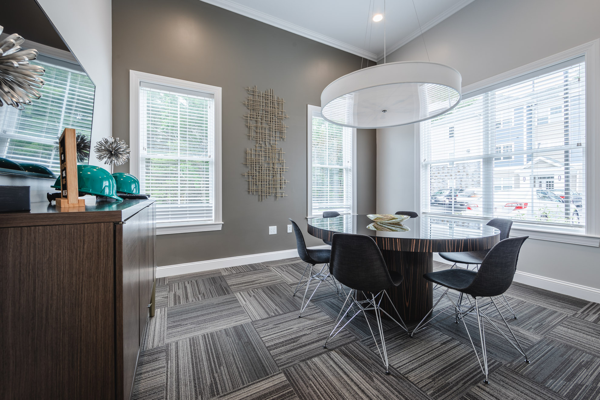 Elegant dining area featuring a sleek glass table, modern black chairs, and abundant natural light from large windows.