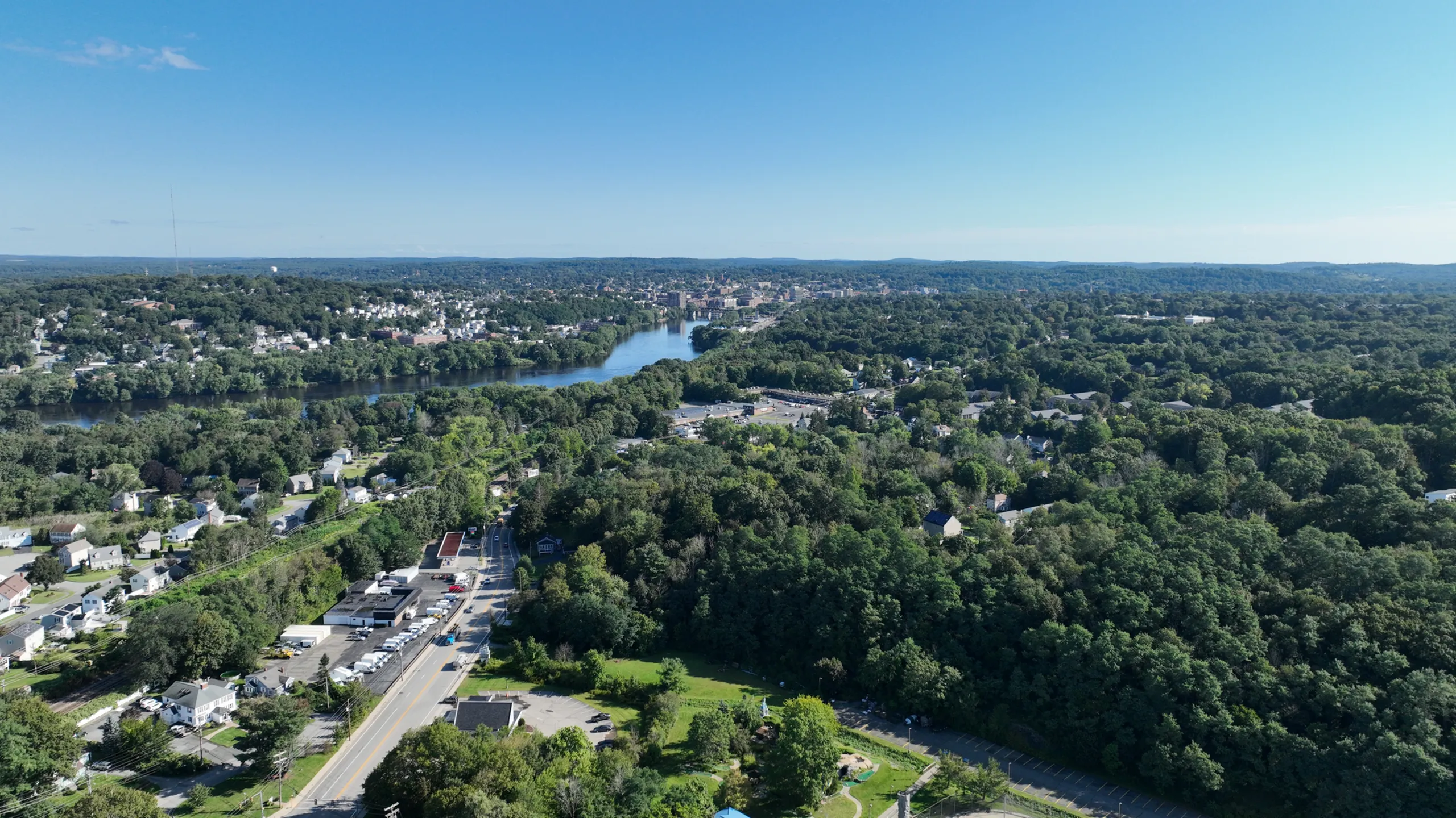 Scenic aerial view of a lush green riverside of the merrimack river with winding roads and residential buildings in haverhill ma