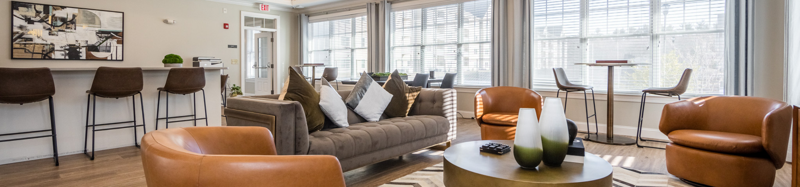 Inviting modern living room with elegant decor, featuring plush seating, stylish bar area, and abundant natural light from wide windows.