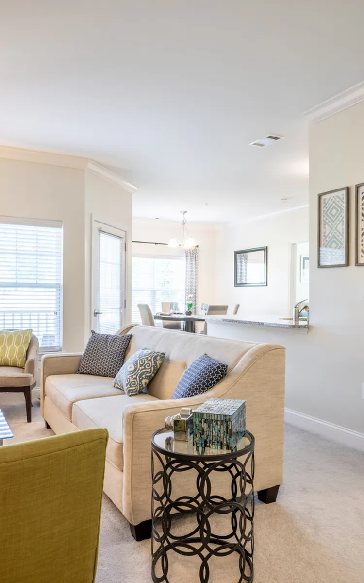 Inviting living room with elegant beige sofa, modern decor, and abundant natural light, seamlessly connected to a dining area showcasing a stylish ambience.