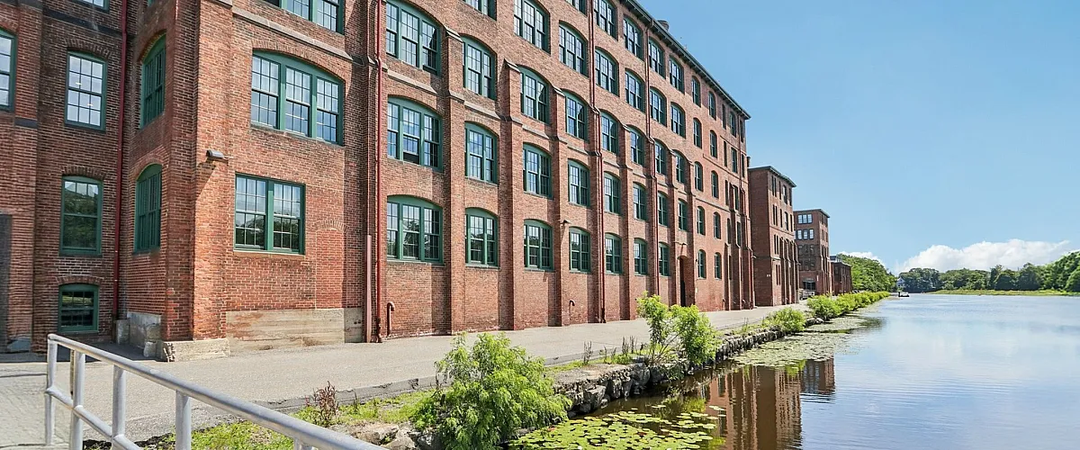 Charming riverside brick building amidst a serene landscape, ideal for waterside living and tranquil views.