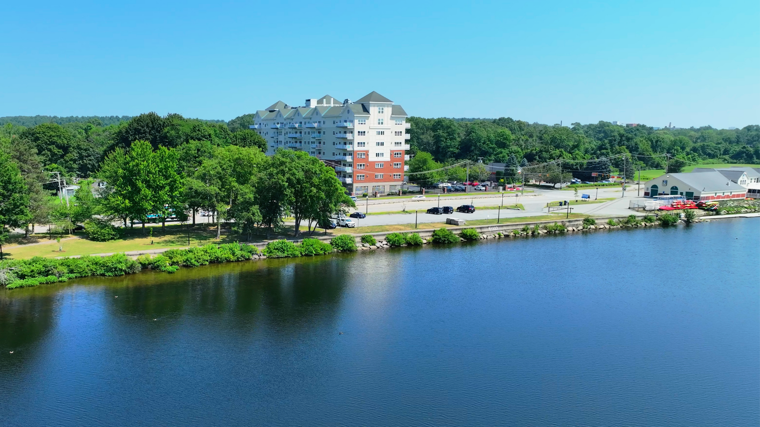 Charming riverside apartment building surrounded by lush greenery, offering serene water views and modern living.