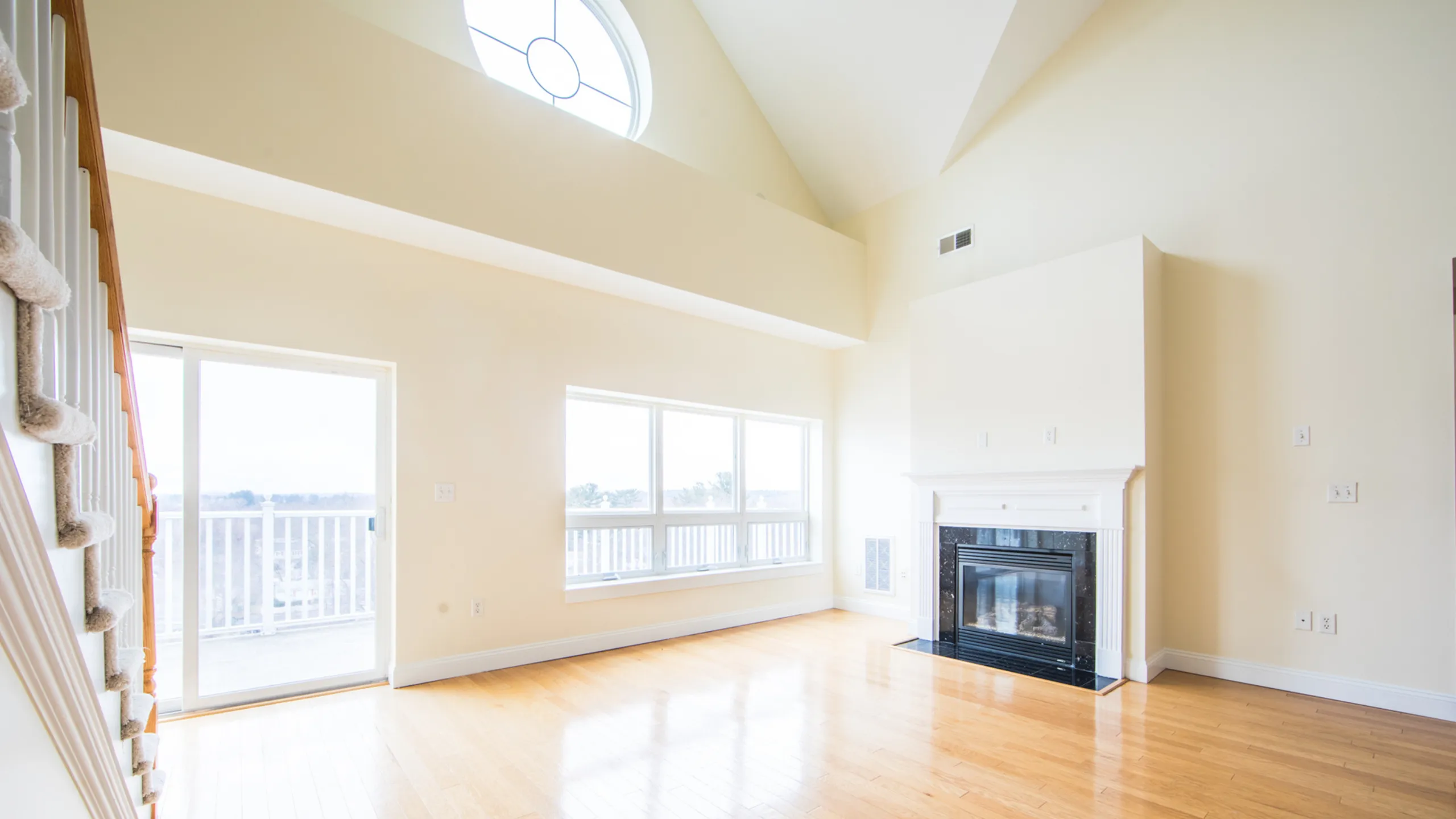 Bright and airy living room with a vaulted ceiling and large windows letting in natural light, featuring a cozy fireplace and elegant wooden flooring.